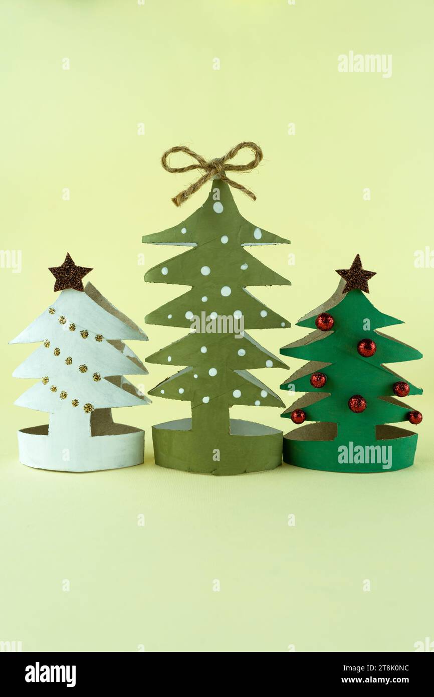 Handgemachte kreative Weihnachtsbäume aus Karton auf gelbem Hintergrund Stockfoto