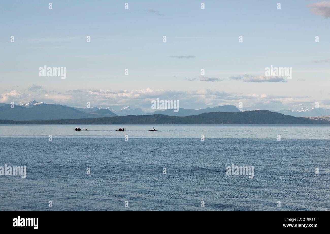 Silhouette von Kajaks und Ruderbooten mit Bergen im Hintergrund, Strait of Georgia, British Columbia, Kanada Stockfoto