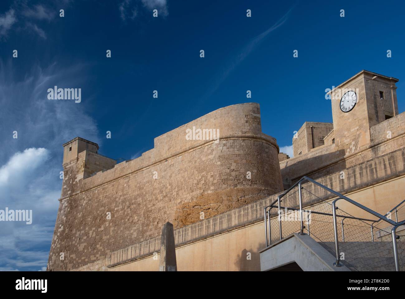 Nahaufnahme der hohen Mauer der historischen Zitadelle auf Gozo in Malta. Die starken Mauern ragen hoch. Der Himmel ist blau mit hellen Wolken. Stockfoto