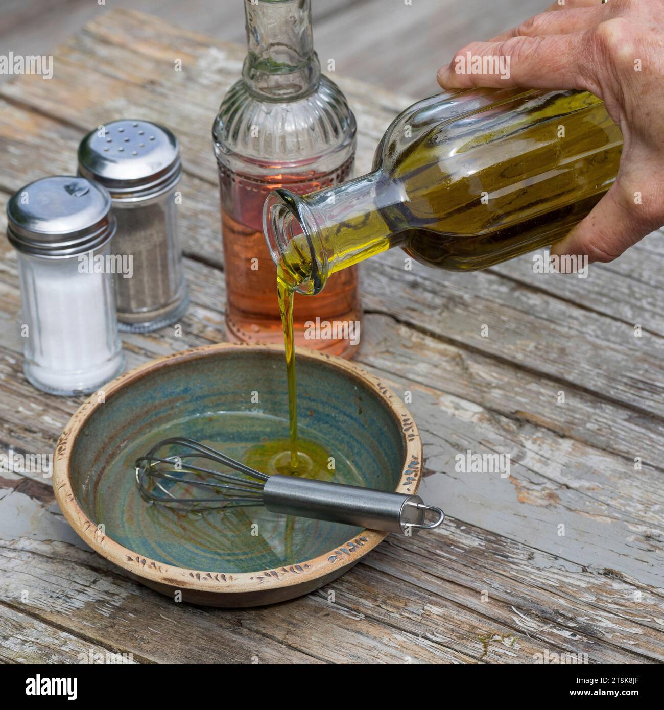 selbstgemachtes Dressing für Kräutersalat, Essig, Öl, salz und Pfeffer werden in einer Schüssel gerührt Stockfoto