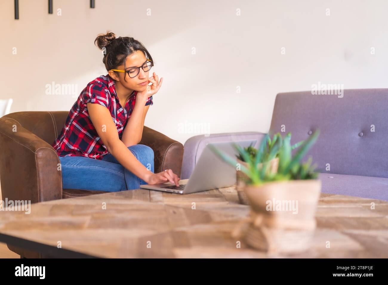 Konzentrieren Sie sich auf eine junge Geschäftsfrau, die von zu Hause aus mit einem Laptop arbeitet Stockfoto