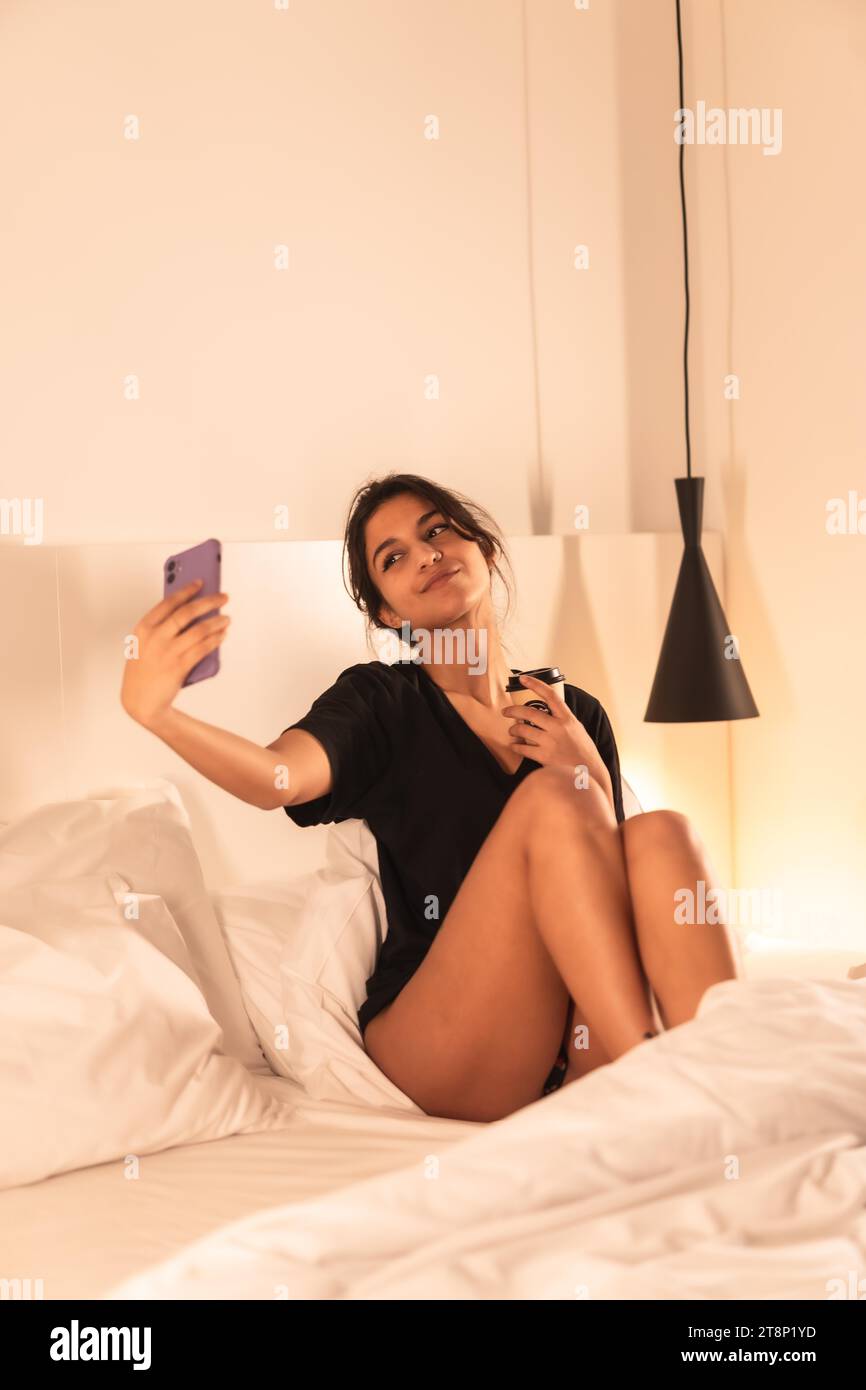 Vertikales Porträt einer jungen Schönheitsfrau, die für soziale Medien posiert, während sie in einem Hotel aufwacht Stockfoto