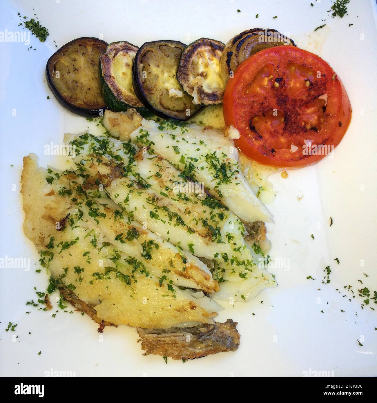 Mediterranes Gericht für gesunde Ernährung nach italienischem Rezept mit gegrilltem Seezungenfilet, bestreut mit gehackter Petersilie und leicht frittiertem Stockfoto