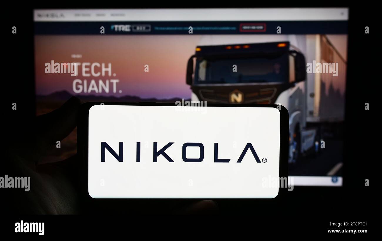 Person mit Smartphone und Logo des US-amerikanischen Elektrofahrzeugunternehmens Nikola Corporation vor der Website. Schwerpunkt auf dem Display des Telefons. Stockfoto