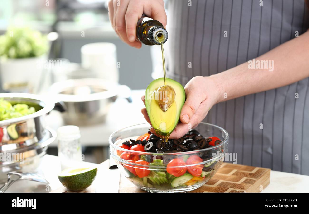 Männliche Hände goß Öl halbiert Tropischen Avocado Stockfoto