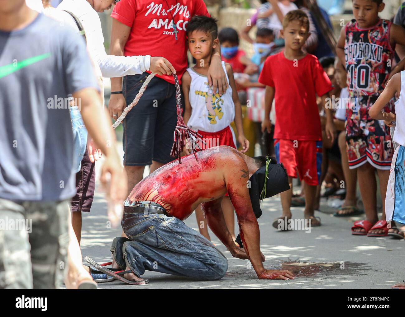 Ängstliches Kind, das einen blutenden Flagellant beobachtet, während ein Teenager den Buße peitscht, Karwoche, Karfreitag, Philippinen-Ritual, Maleldo, echte Kreuzigung Stockfoto