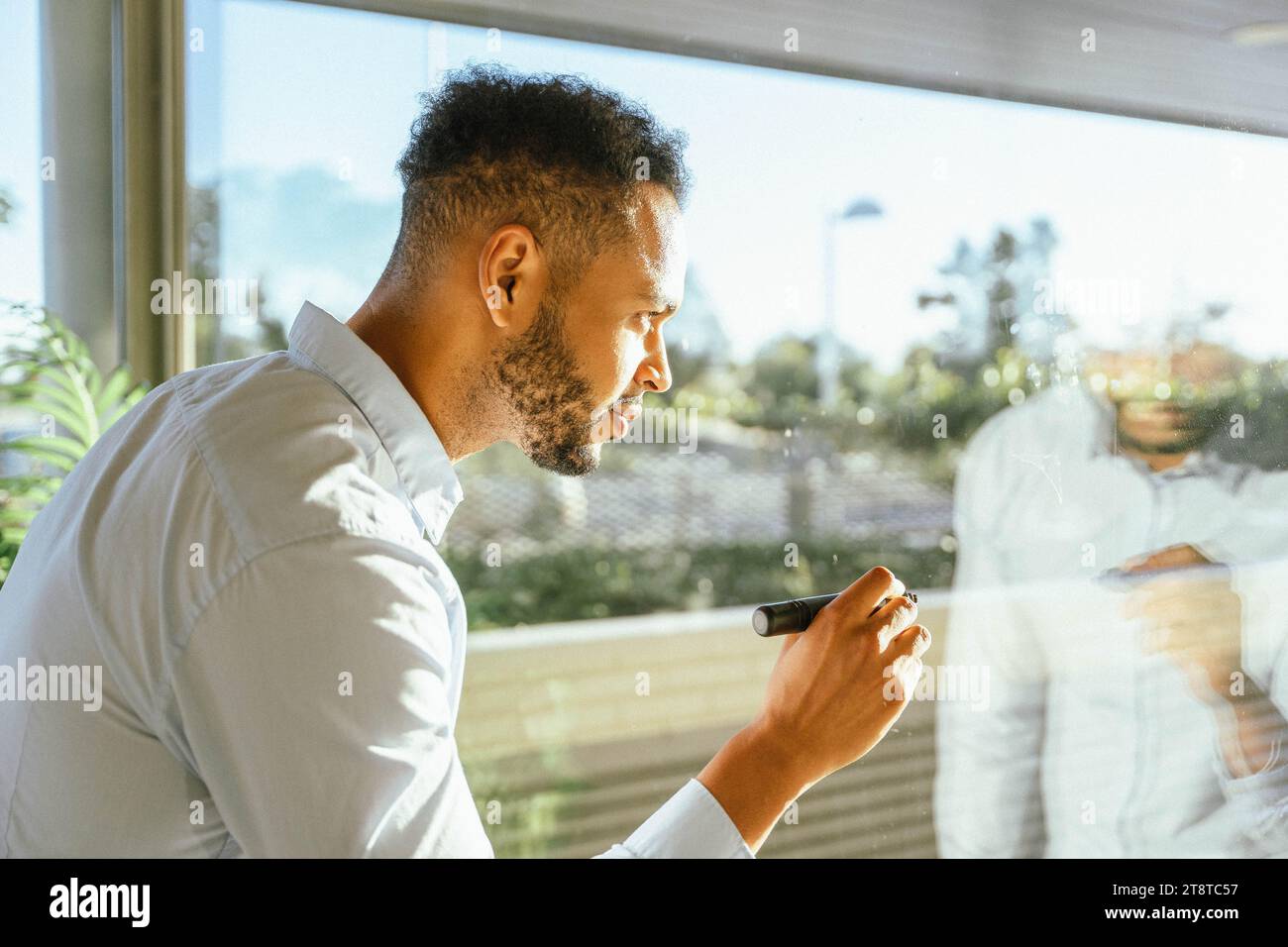 Professioneller Geschäftsmann, der Ideen an das Fenster schreibt, während er an einem Startup-Projekt arbeitet. Business- und Brainstorming-Konzept. Stockfoto