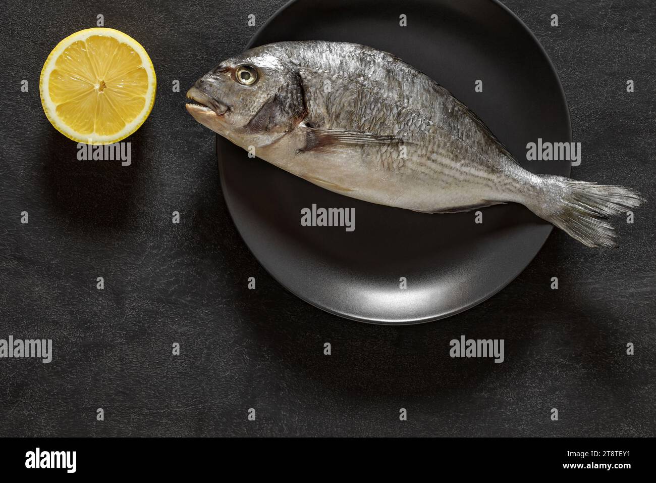 Dorado, roher frischer, ungekochter Fisch, Quelle von Omega 3, Zitronengelb, auf dunklem Hintergrund, Draufsicht, Platz zum Kopieren von Text Stockfoto