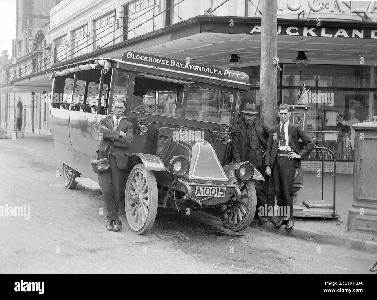 Blockhouse Bay, Avondale und Pitt Street Bus und Fahrer, Auckland, Neuseeland, View of a Bus, der zwischen Blockhouse Bay, Avondale und Pitt Street, Auckland, Neuseeland, verkehrte, mit dem Fahrer und zwei anderen unbekannten Männern. Der Bus hat ein internationales Busfahrgestell. (Ca. 1920s). Der Bus parkt vor den Gebäuden der Auckland, New Zealand Gas Company Ltd an der Ecke Pitt Street und Beresford Square Stockfoto
