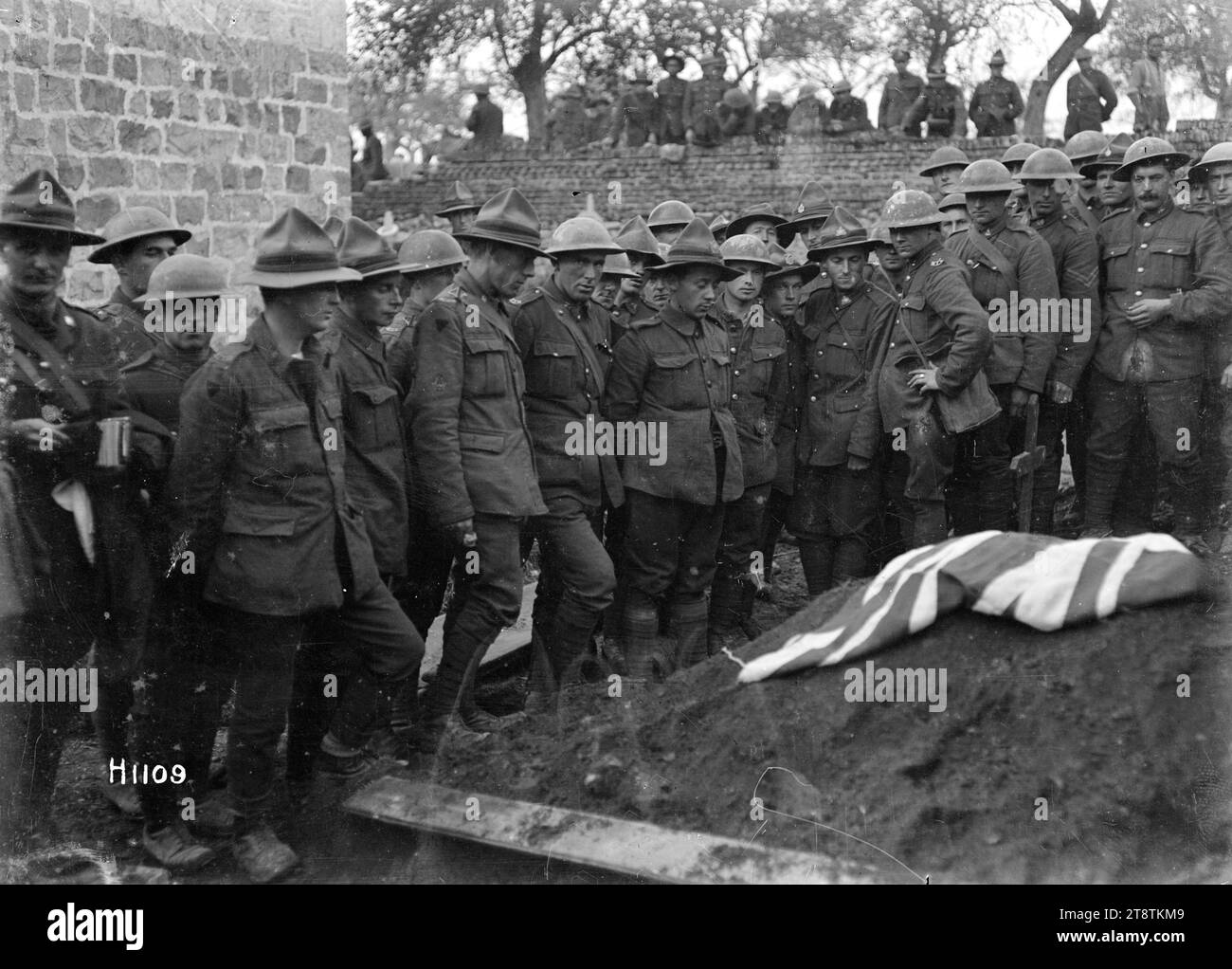 Die Beerdigung von Sergeant Henry Nicholas, VC, im Ersten Weltkrieg, Frankreich, versammeln sich neuseeländische Soldaten um das Grab bei der Beerdigung von Sergeant Henry James Nicholas, VC, MM, der gegen Ende des Ersten Weltkriegs getötet wurde Andere Soldaten beobachten von der Mauer eines französischen Kirchhofs aus. Foto wahrscheinlich am 9. November 1918 auf dem Kirchhof Vertigneul bei Romeries, Frankreich Stockfoto