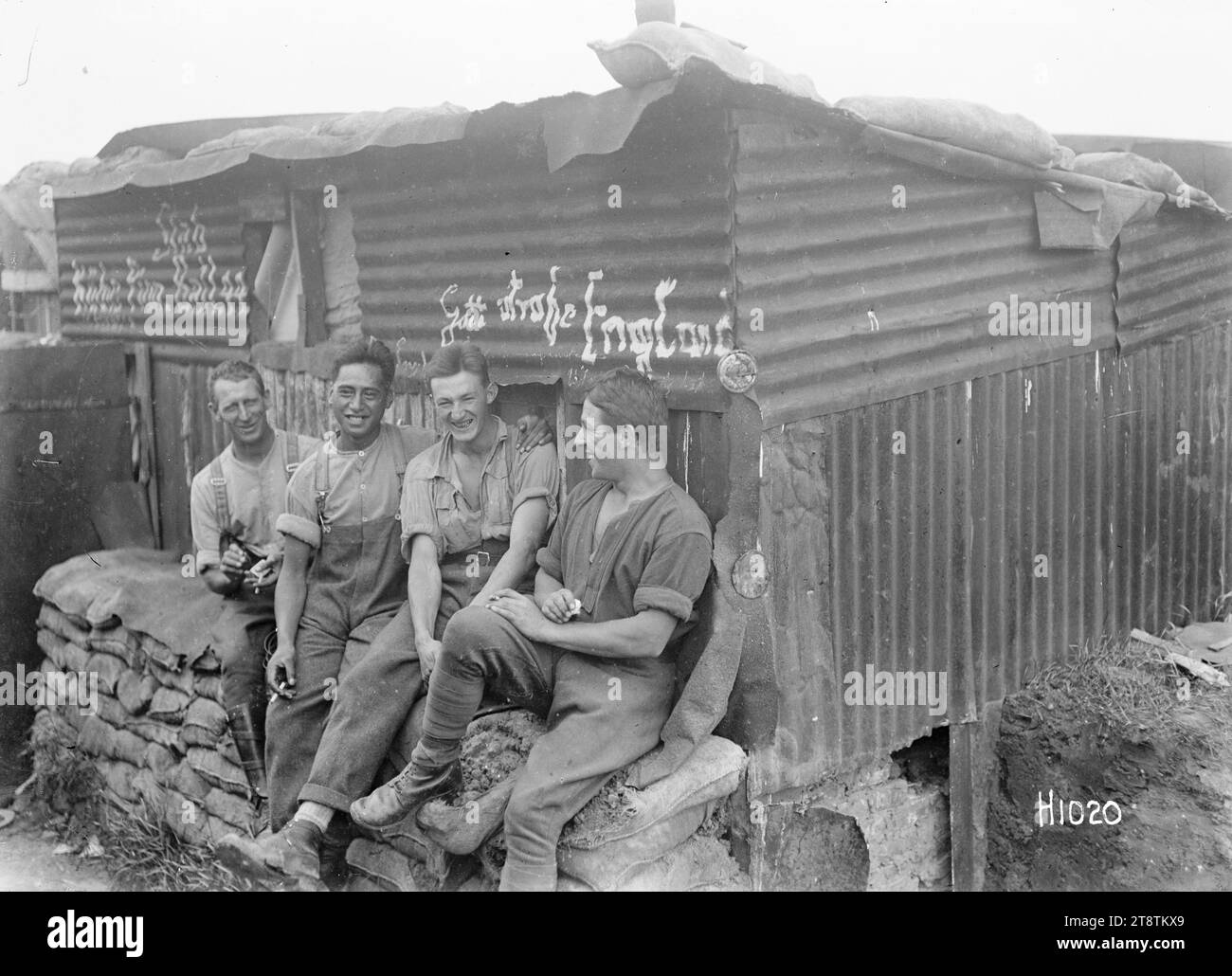 Neuseeländische Soldaten vor einer deutschen Hütte, vier Soldaten aus dem Ersten Weltkrieg, die auf einer Sandsäckwand vor einer Wellblechhütte sitzen, die von den Deutschen gefangen genommen und in ihr Hauptquartier verwandelt wurde. Foto zwischen 1914 und 1918 Stockfoto