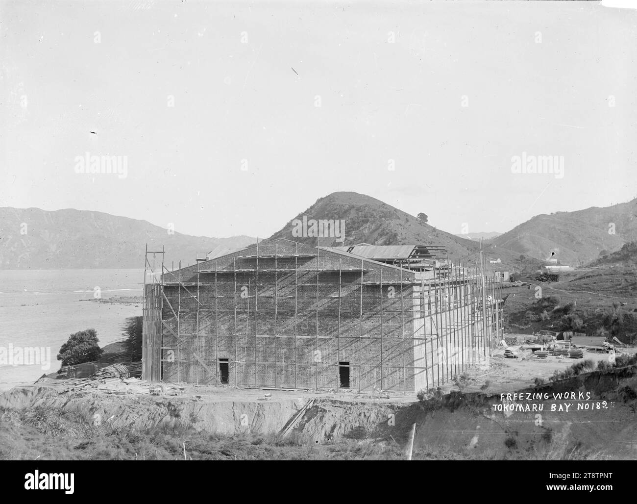 Tokomaru Sheepfarmers' Freezing Company Ltd. Arbeitet im Bau in Waima, Tokomaru Bay, Ostküste, Tokomaru Bay Freezing Works, die ein großes Gebäude im Bau mit Gerüsten umgibt. Blick nach Süden Anfang der 1900er Jahre Stockfoto