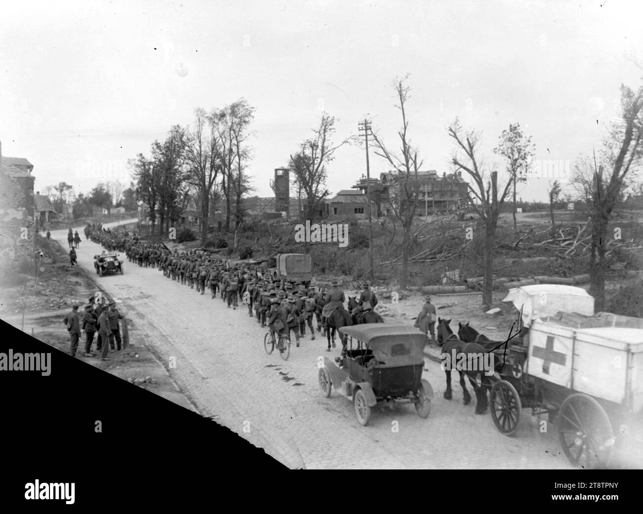 Ein neuseeländisches Bataillon, das durch das zurückeroberte Bapaume im Ersten Weltkrieg durchquert, Ein Blick von der Rückseite eines neuseeländischen Bataillons, das durch das zurückeroberte Bapaume in Frankreich führt. Zeigt einen Pferdewagen hinter einer Truppenkolonne, die meist zu Fuß eine Straße hinunterfährt. Ein paar Männer sind auf dem Berg und ein anderer fährt mit dem Fahrrad. Auch Autos sind unterwegs. Im Hintergrund befindet sich die schwer beschädigte Zuckerfabrik vom 14. September 1918 Stockfoto