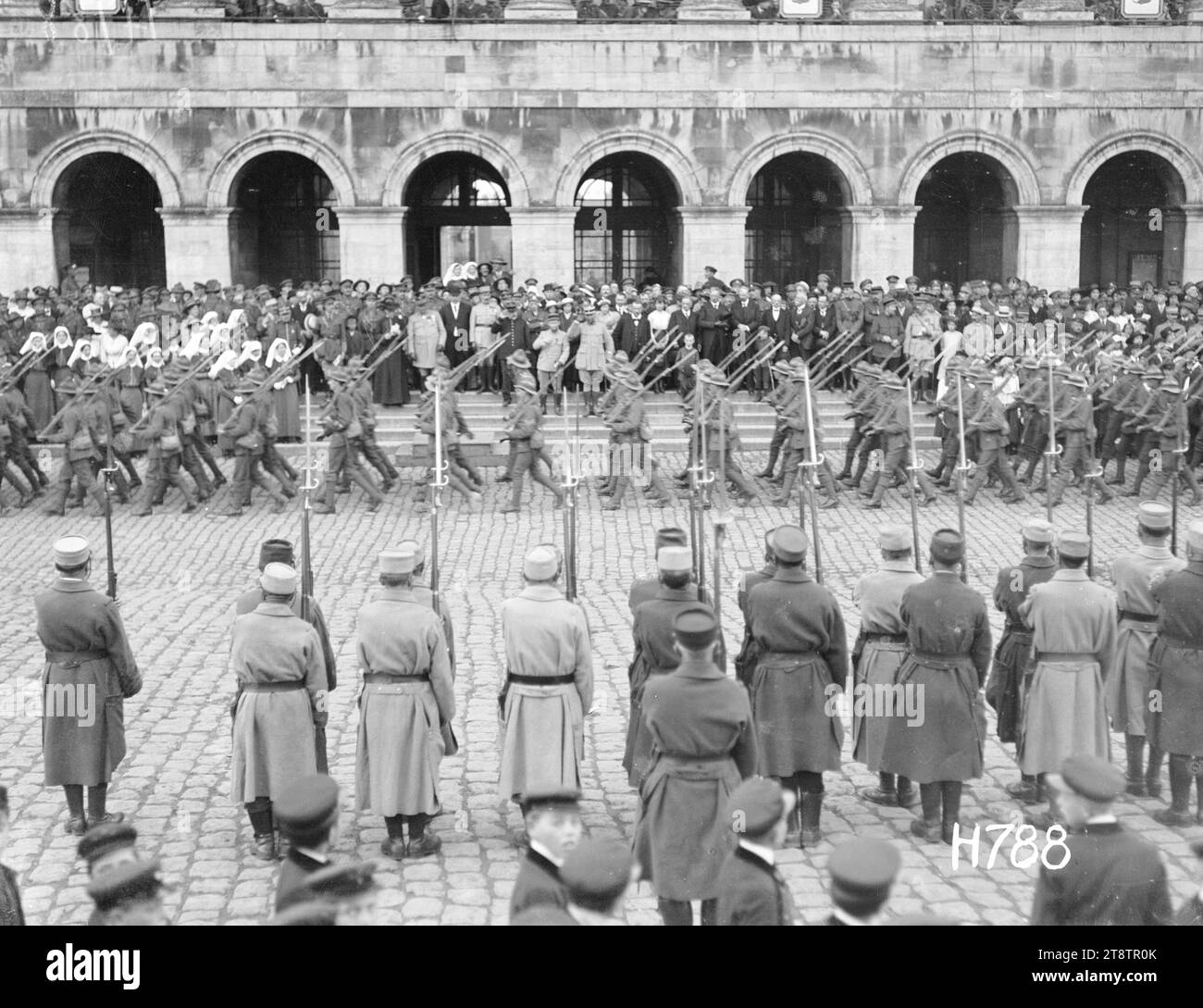 Neuseeländische Truppen marschieren am Fete National, Hazebrouck, Ein allgemeiner Blick über den Stadtplatz der neuseeländischen Truppen, die bei den offiziellen Feierlichkeiten für den Fete National, Hazebrouck, vorbeimarschieren. Beamte und Gäste stehen auf den Stufen des Rathauses? Links stehen Schwestern aus dem stationären Krankenhaus NZ. Im Vordergrund stehen französische Soldaten, 14. Juli 1917 Stockfoto
