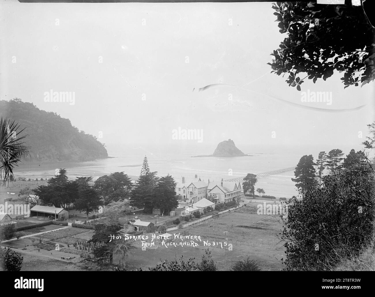 Hot Springs Hotel, Waiwera, Blick auf das Hot Springs Hotel und die Gärten in der Nähe des Strandes von Waiwera. Von der Hauptstraße von Auckland, Neuseeland (State Highway 1) aus blickten wir auf das Hotel und die Umgebung. Mahurangi Island kann vor der Küste gesehen werden, links vom Kai. Anfang der 1900er Jahre Stockfoto