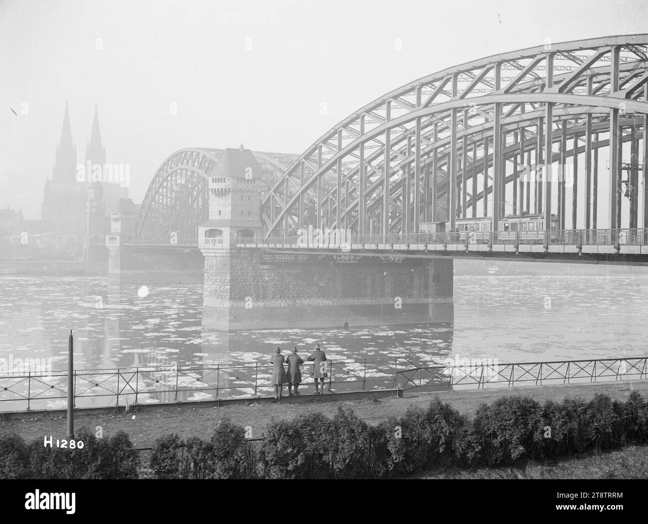 Neuseeländische Soldaten schauen auf die Hohenzollernbrücke, Köln, nach dem Ersten Weltkrieg sehen drei neuseeländische Soldaten vorne auf die Hohenzollernbrücke über den Rhein in Köln, Deutschland, nach dem Ersten Weltkrieg Straßenbahnwagen sind auf der Brücke. Eis schwimmt auf dem Fluss. Im Hintergrund ist auch der Kölner Dom zu sehen. Foto aufgenommen im Januar 1919 Stockfoto