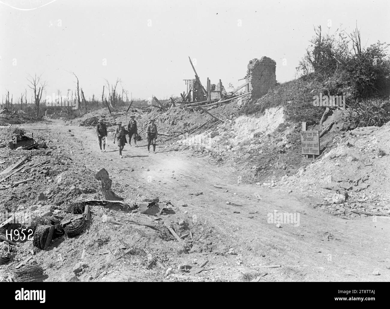 Soldaten, die entlang der Hauptstraße nach Puisieux laufen, Soldaten, die zwischen bombardierten Gebäuden entlang der Hauptstraße nach Puisieux spazieren. Am Straßenrand ist ein deutsches Verkehrszeichen zu sehen. Foto, das während des Ersten Weltkriegs aufgenommen wurde Stockfoto