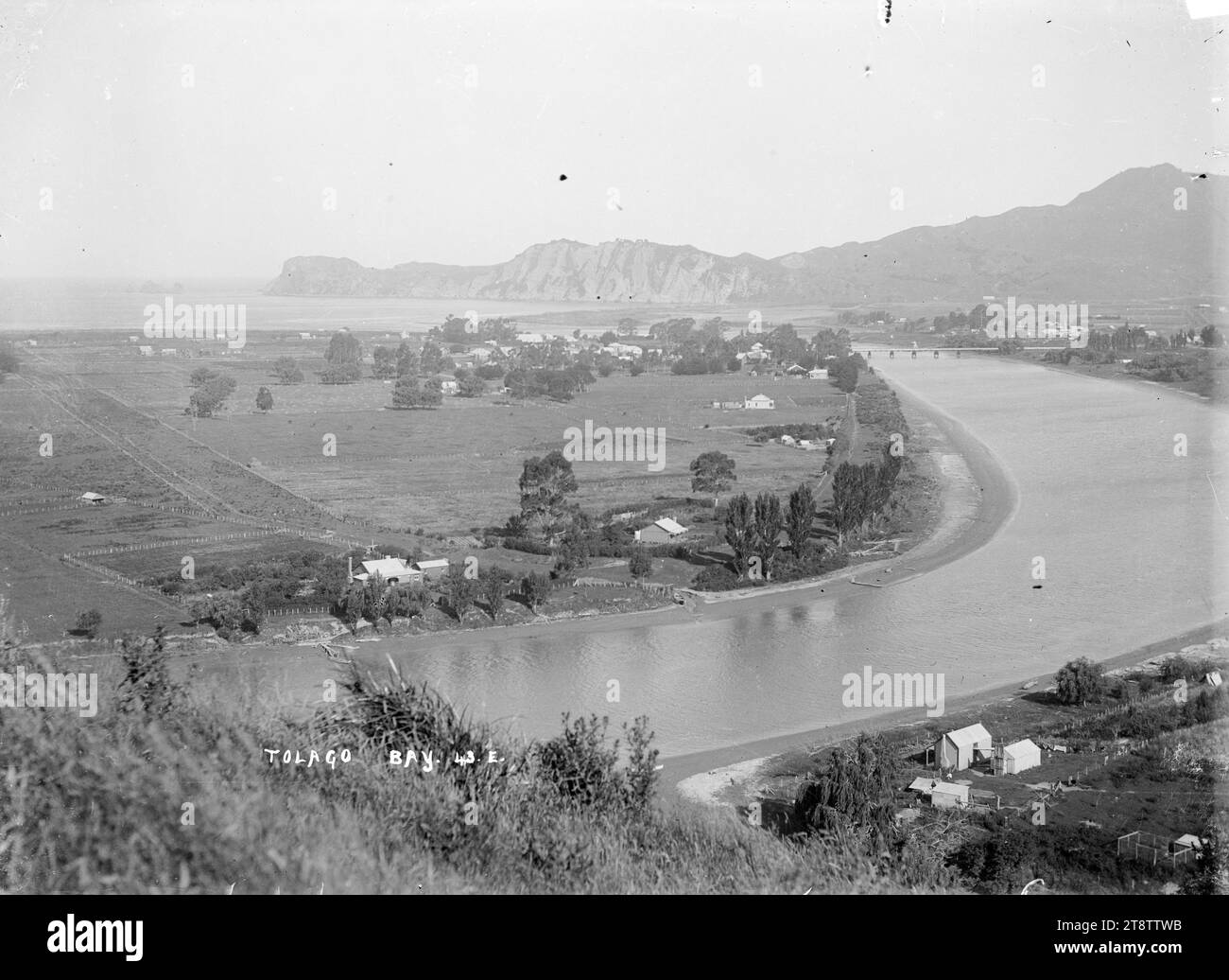 Uawa River, Tolaga Bay, Blick südöstlich von Tolaga Bay mit dem Uawa River im Vordergrund und rechts. Das Township und die Brücke sind in der mittleren Distanz zu sehen, und die Küstenlinie und Mitre Rocks in der Ferne. Foto aufgenommen um 1900-1930 Stockfoto