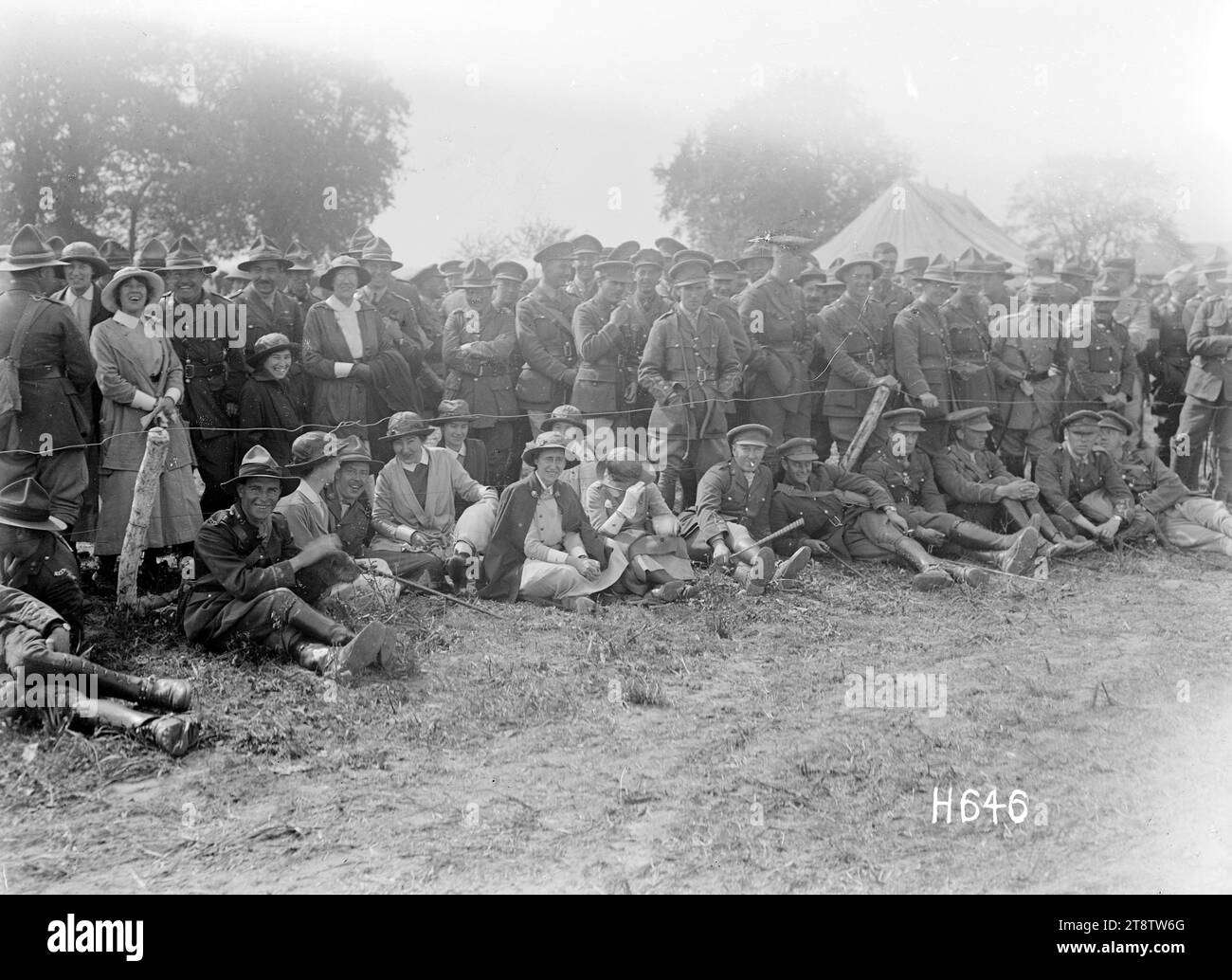 Kanadische Krankenschwestern besuchen die Pferdeschau der New Zealand Infantry Brigade in Frankreich, Eine Gruppe kanadischer Krankenschwestern aus dem nahe gelegenen kanadischen Krankenhaus (einige sitzen auf dem Gras), die in Begleitung von neuseeländischen Soldaten auf der Pferdeschau der New Zealand Infantry Brigade während des Ersten Weltkriegs in Vaucelles stattfanden Foto vom 1. Juni 1918 von Henry Armytage Stockfoto