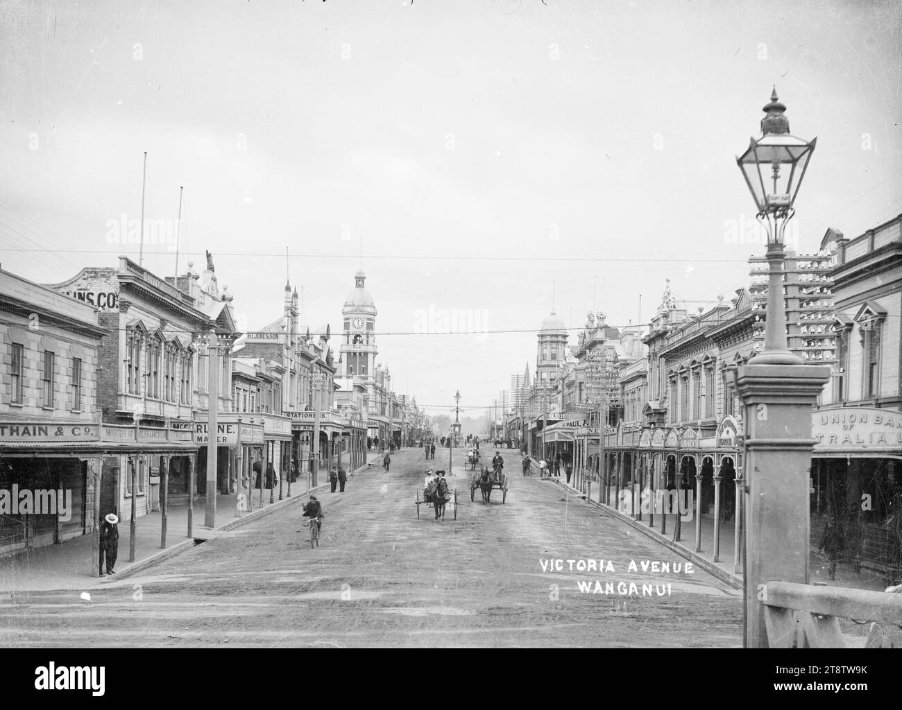Blick auf Victoria Avenue, Wanganui, Neuseeland, Blick auf Victoria Avenue, Wanganui, Neuseeland von der City Bridge. Der Uhrturm der Post ist in der Mitte links zu sehen, die Straße ist von Geschäften gesäumt, und es kommen mehrere Pferdewagen, die auf die Kamera zufahren. In der Mitte des Bildes ist der Watt-Brunnen zu sehen. Vor Dezember 1908. Der Brunnen wurde verlegt, um Platz für eine neue Straßenbahnlinie zu schaffen, die im Dezember 1908 eröffnet wurde Stockfoto