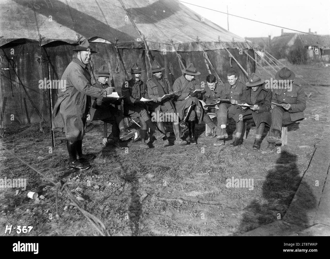 Die Kiwis lernen ihre Teile für eine Pantomime während des Ersten Weltkriegs, die Kiwis lernen ihre Teile für die Pantomime „die vierzig Diebe“, die am zweiten Weihnachtsfeiertag produziert werden soll. Zeigt die Männer, die vor einem Zelt sitzen, mit ihren Drehbüchern. Die stehende Figur ganz links wurde (von einem Verwandten) als Dave Kenny identifiziert. Foto in der Nähe von Dickebusch, Belgien, am 21. Dezember 1917 Stockfoto