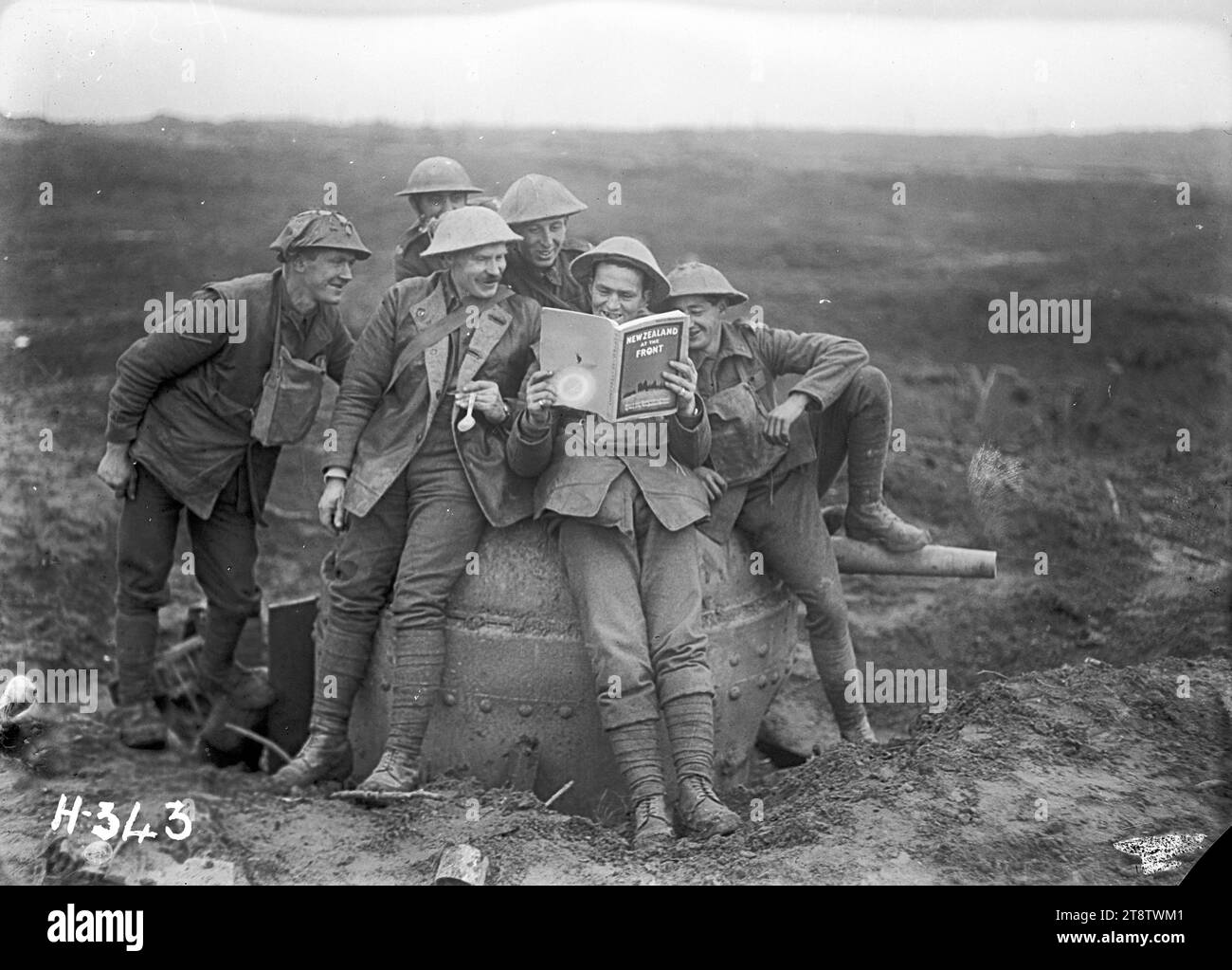 Neuseeländische Soldaten aus dem Ersten Weltkrieg mit einer Kopie von „New Zealand at the Front“, Einer Gruppe von Soldaten des 3. Bataillons, der NZ Rifle Brigade, genießen den Witz, eine Kopie der Publikation „New Zealand at the Front“ zu lesen, während sie auf einer gefangenen deutschen Panzerabwehrkanone sitzen. Foto aufgenommen am 20. November 1917 in „Clapham Junction“, einem schlammigen Teil des Schlachtfeldes in Belgien Stockfoto