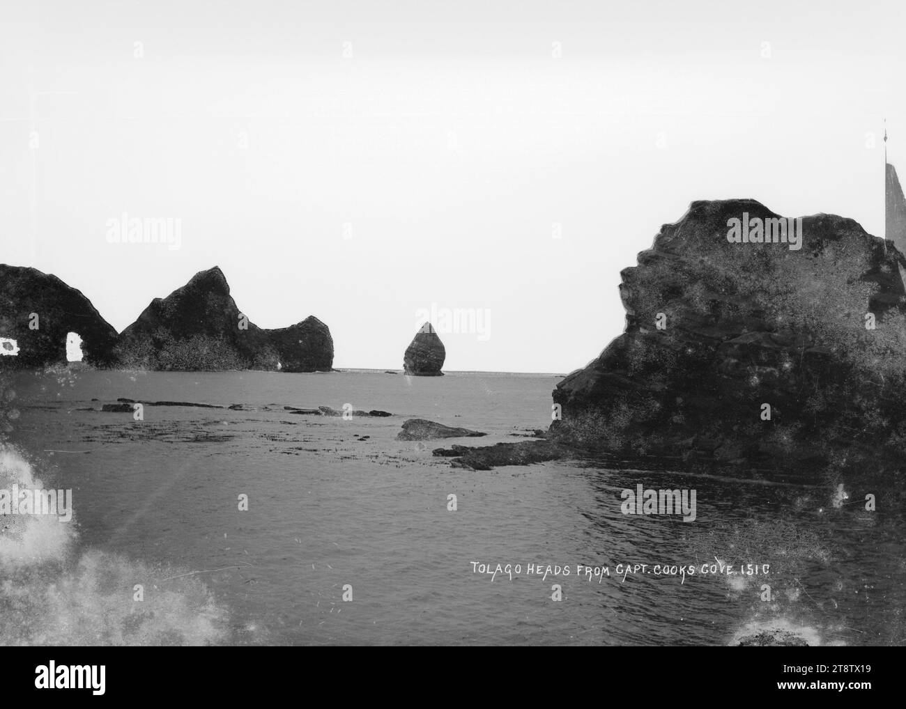 Tolaga Heads von Captain Cook's Cove, Blick auf Tolaga Heads von Captain Cook's Cove, Gisborne. Zeigt schroffe Felsformationen, bekannt als „die Haystacks“ am Eingang zum Hafen. Foto zwischen 1906 und 1912 Stockfoto
