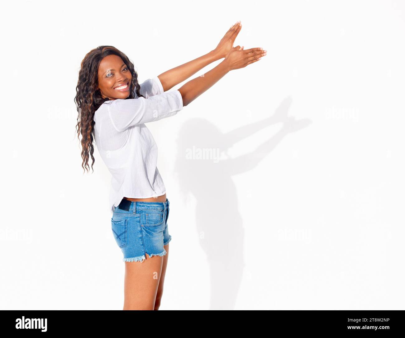 Vogelschatten, schwarze Frau und Porträt mit Händen in Flügelform fliegen in einem Atelier. Glücklich, lächelnd und afrikanische weibliche Person mit modernem und zwanglosem Ambiente Stockfoto