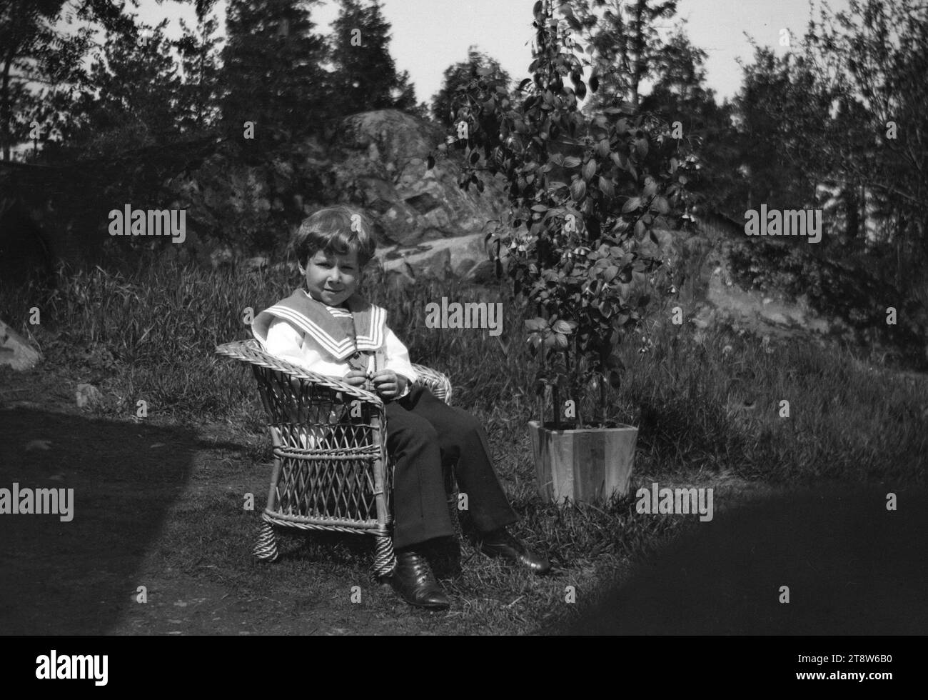 Hugo Simberg, 24.6,1873, Hamina, 12.7,1917, Ähtäri, Tom Simberg in seinem Matrosenanzug in Ähtäri, 1917, 56 x 83 mm, Korbstuhl, Blume, Matrosenanzug, Hof - Arbeit: zwei Laubbäume, deren Spitzen zu einem verschmelzen Stockfoto