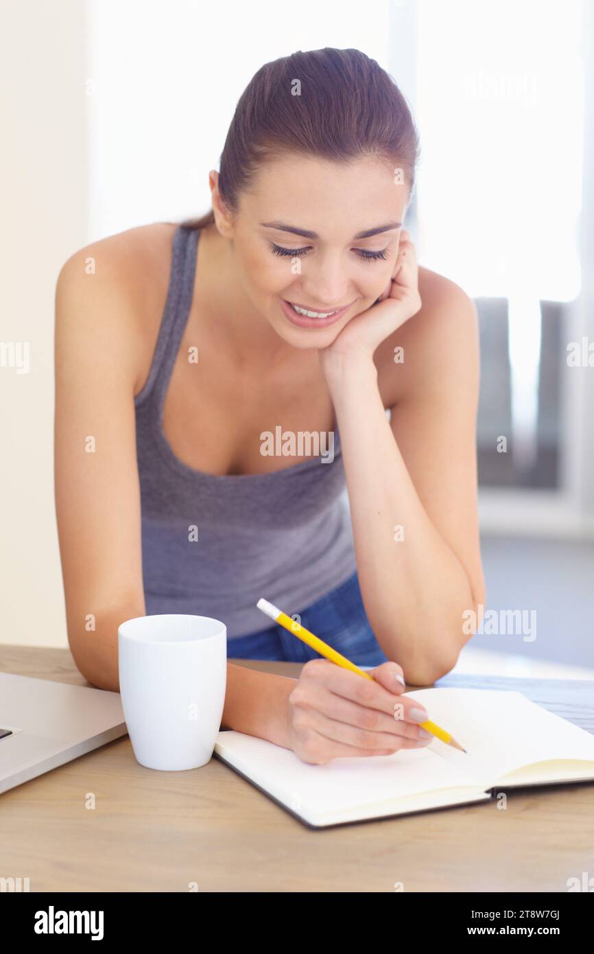Kaffee, Notizbuch und eine Frau, die morgens in der Küche ihres Hauses schreibt, um Bildung oder Journalismus zu studieren. Tee, Tagebuch und ein glücklicher junger Mensch in ihr Stockfoto