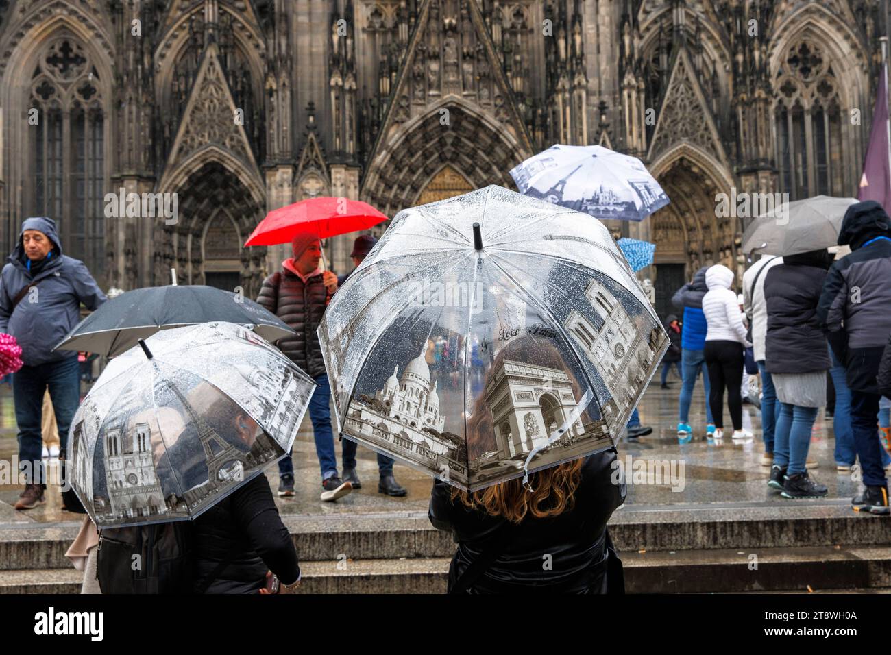 Touristen mit Sonnenschirmen im Pariser Stil vor dem Dom, Köln, Deutschland. Touristen mit Regenschirmen mit Paris Motiven stehen bei Regen vor d Stockfoto
