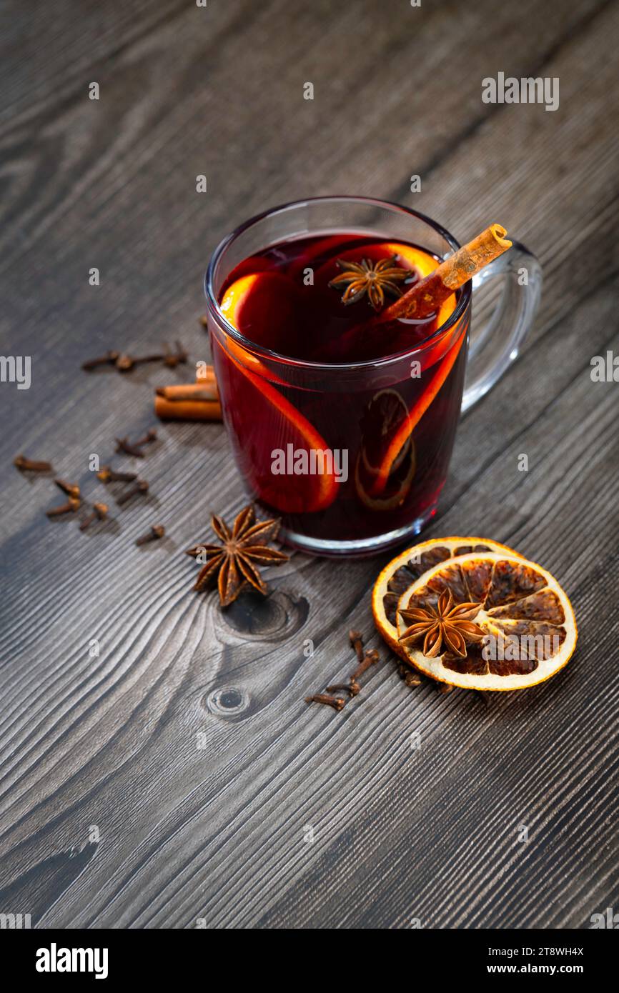 Glas Glühwein mit Orangenscheibe. Glühwein und Zutaten auf einem Holztisch. Handgeführte Aufnahmen Stockfoto