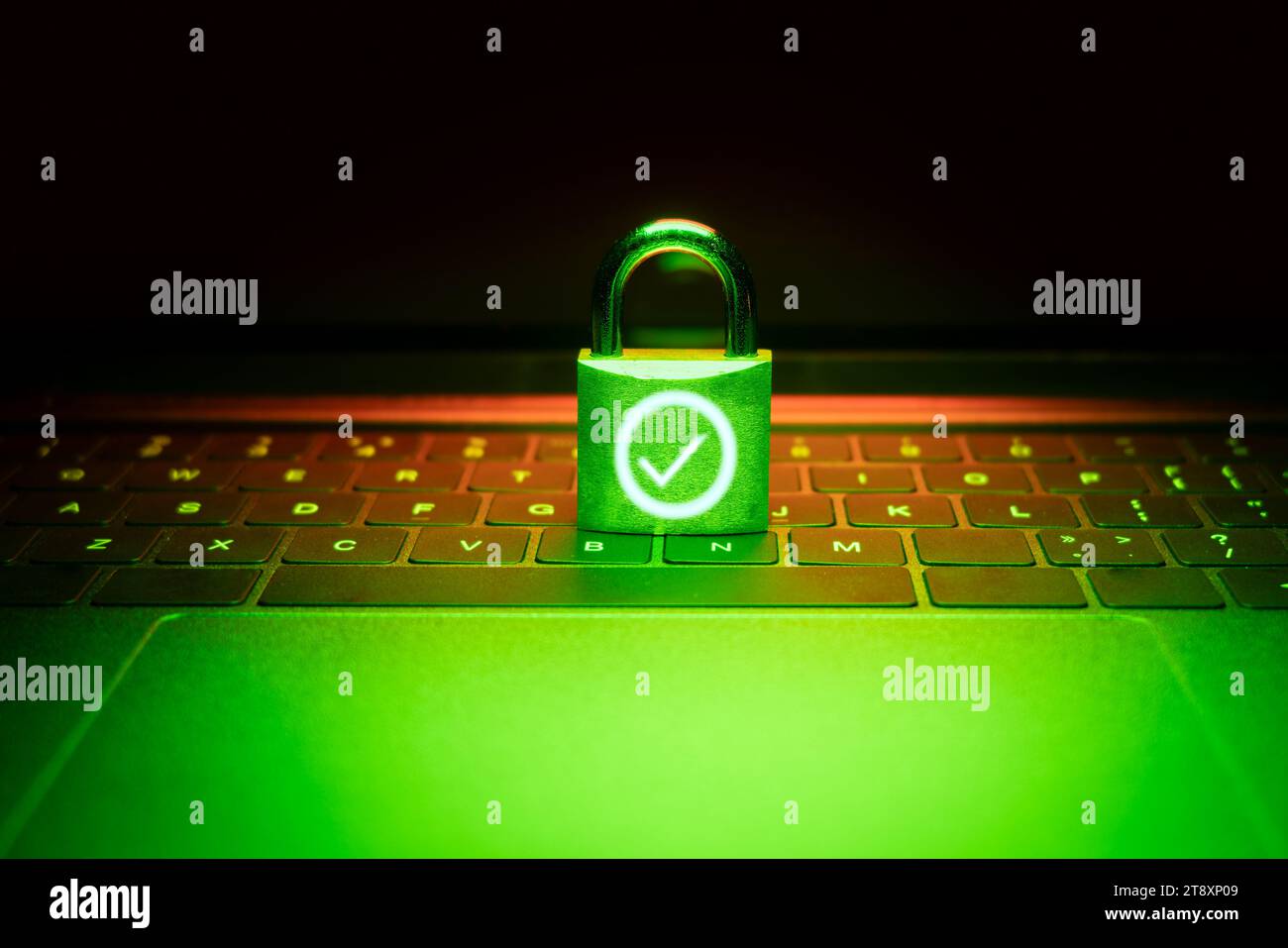 Nahaufnahme eines Vorhängeschlosses auf einem Laptop, der mit grünem Licht beleuchtet ist. Phishing, Cybersicherheitsgefahr oder Ransomware-Angriff. Das Vorhängeschloss wird entsperrt und angezeigt Stockfoto