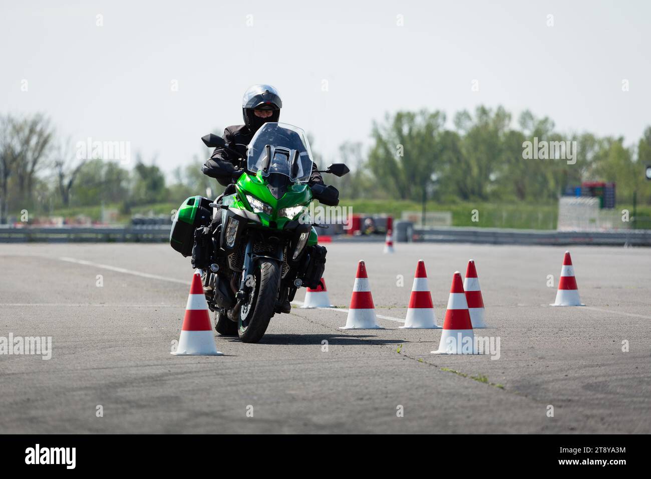 Motorradfahrer auf einem grünen Abenteuerrad, das durch Kegel fährt Stockfoto