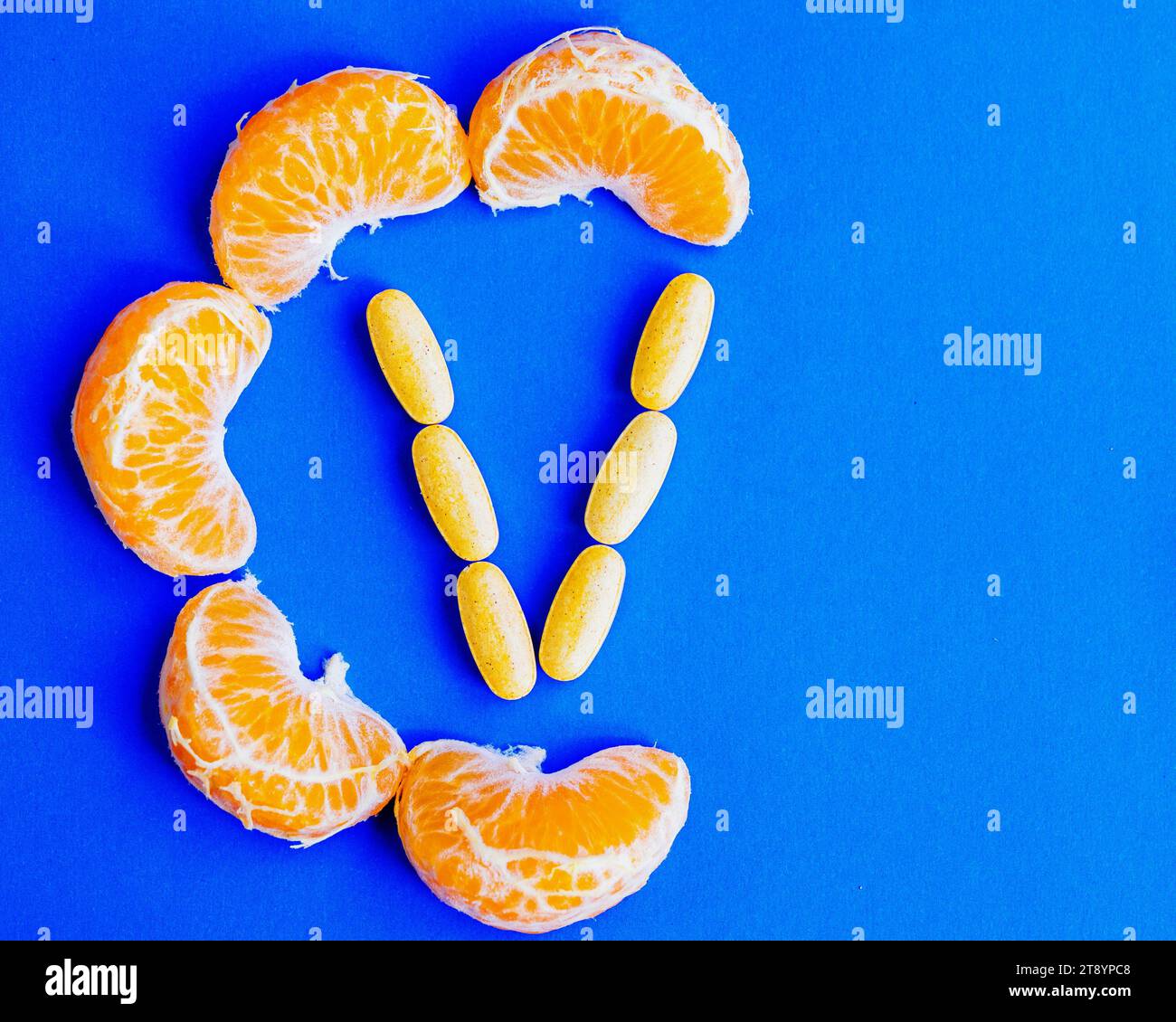 Mandarinenscheiben, die den Buchstaben „C“ bilden, und Vitamin-C-Tabletten, die den Buchstaben „V“ bilden. Das Konzept der künstlichen und natürlichen Vitamin-C-Quellen Stockfoto