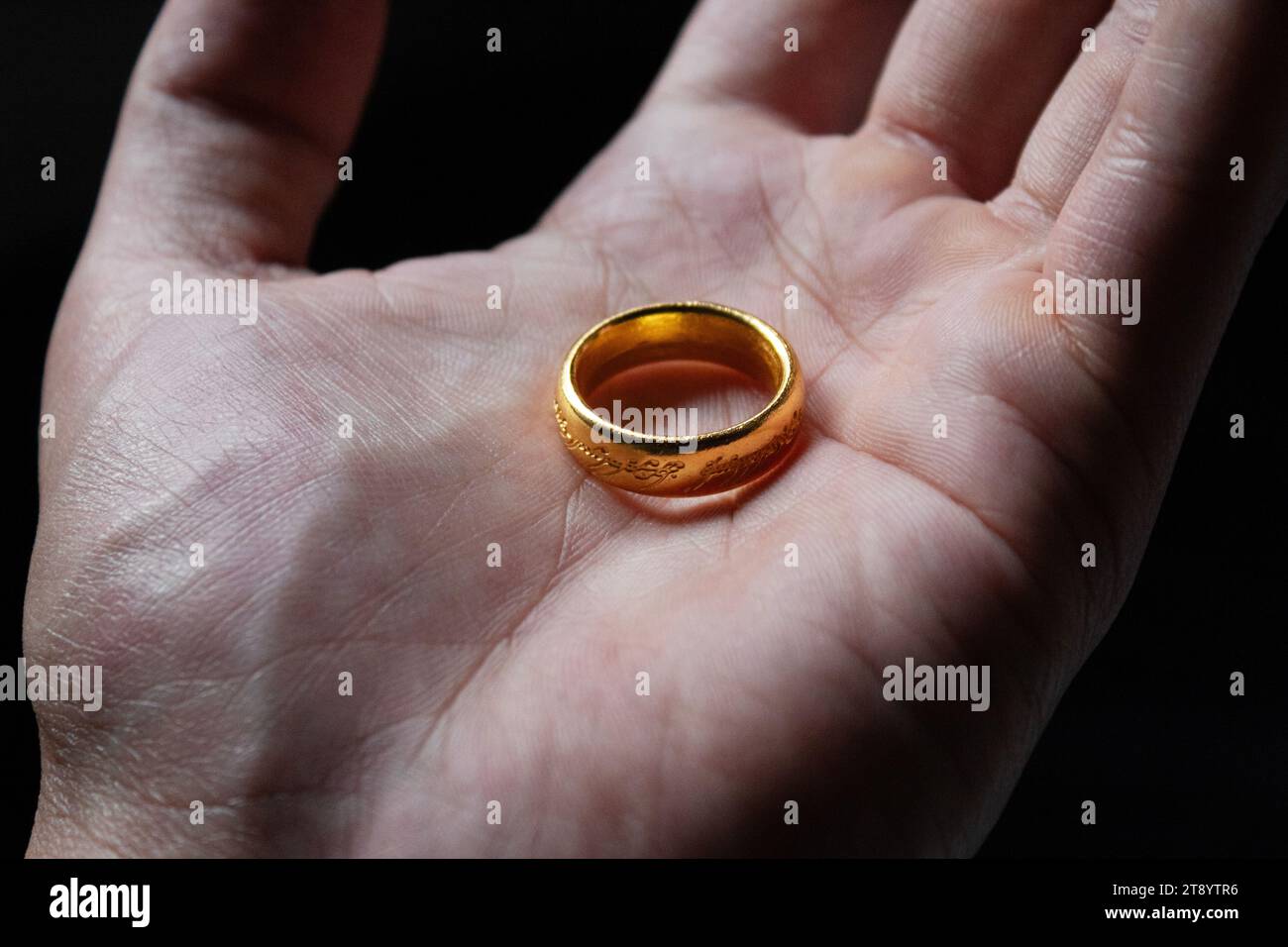 Der Ring des Herrn der Ringe filmt über einer männlichen Hand und dunklem Hintergrund Stockfoto