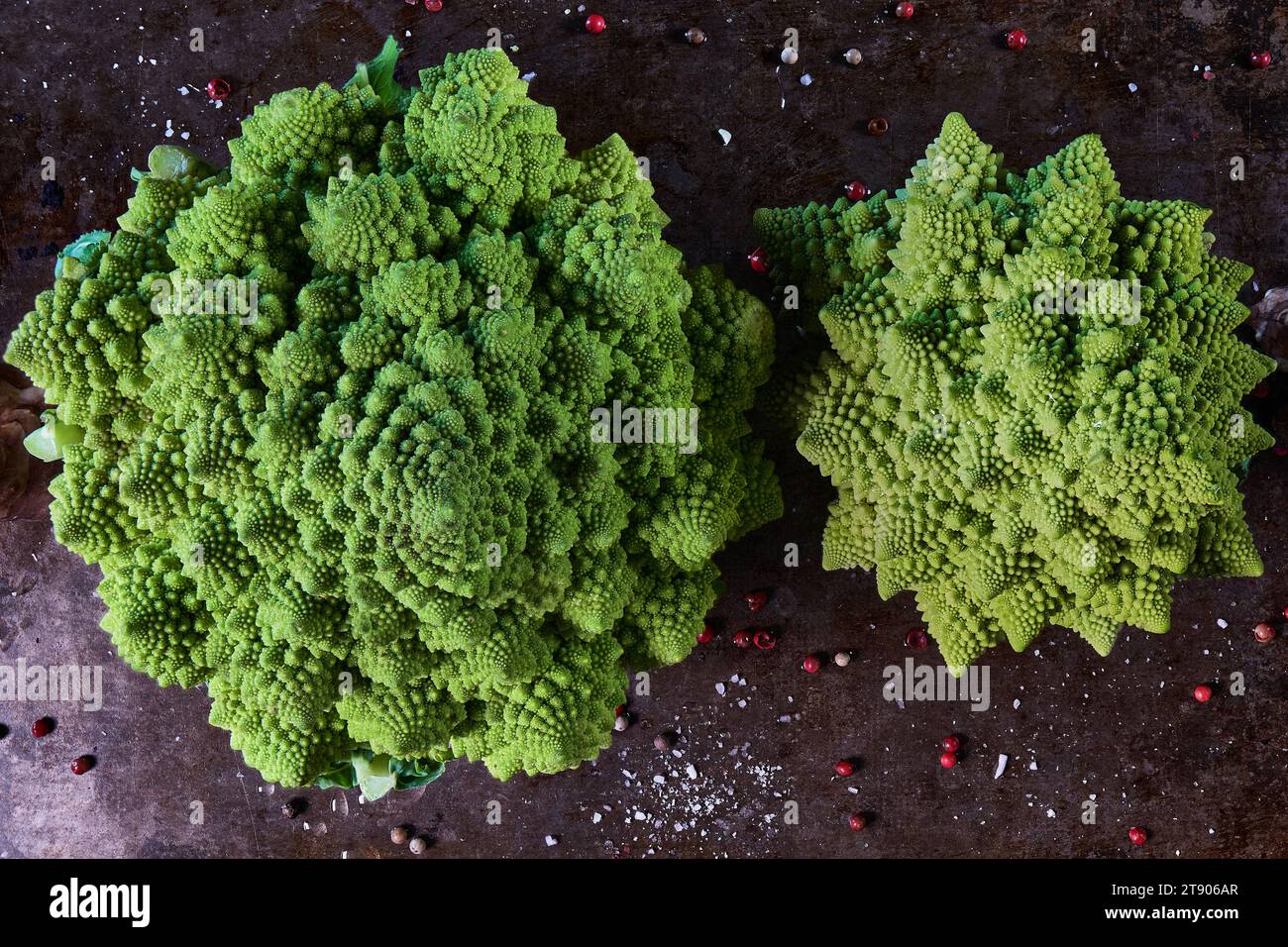 Zwei Romanesco-Kohl auf einem Backblech mit Kräutern, Blick von oben und dunkles Ambiente Stockfoto