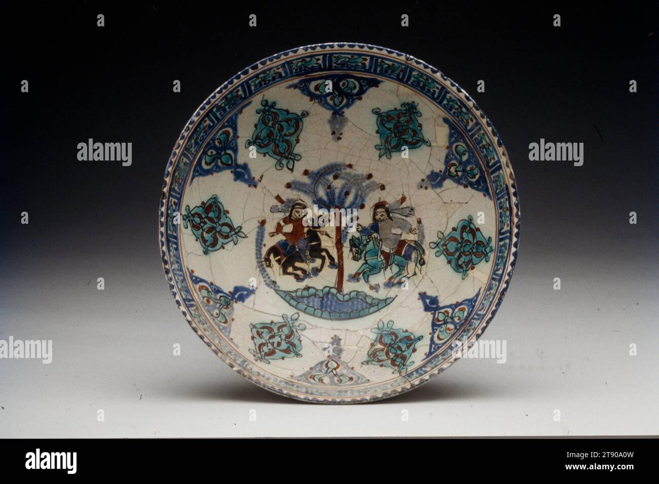 Mina'i Schüssel, 1200-1299, 1/2 x 8 Zoll (8,89 x 20,32 cm), Steinpaste mit Überglasung bemalt, Iran, 13. Jahrhundert, das Thema zweier Reiter auf beiden Seiten eines Baumes erscheint häufig auf mina'i-Waren. Es könnte auf eine Jagdszene angespielt haben, ein Luxus, den die fürstlichen Klassen genießen Stockfoto