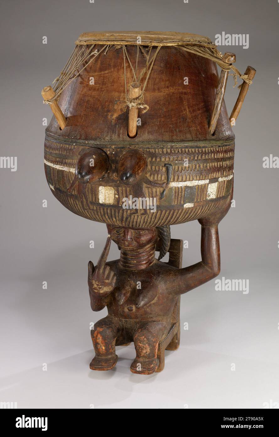 Trommel, ca. 1950, 26 3/16 x 19 1/8 x 16 Zoll (66,52 x 48,58 x 40,64 cm), Holz, Tierhaut, Schnur, Pigmente, Ghana, 20. Jahrhundert, Akan-Gemeinden im Süden Ghanas haben eine Tradition, in der populäre Bands in Instrumental-, Chor- und Tanzaufführungen konkurrieren. Die Meistertrommel, manchmal als „Mutter der Gruppe“ bezeichnet, ist der musikalische und visuelle Mittelpunkt jeder Band. Die Geste der Frau, deren Finger auf ihr Auge zeigt, könnte sich auf das Sprichwort „wenn du hören kannst, kannst du nicht auch sehen“ beziehen, was die Wichtigkeit betont, alle Sinne zu nutzen. Oder es könnte eine Warnung für die anderen Bänder sein Stockfoto