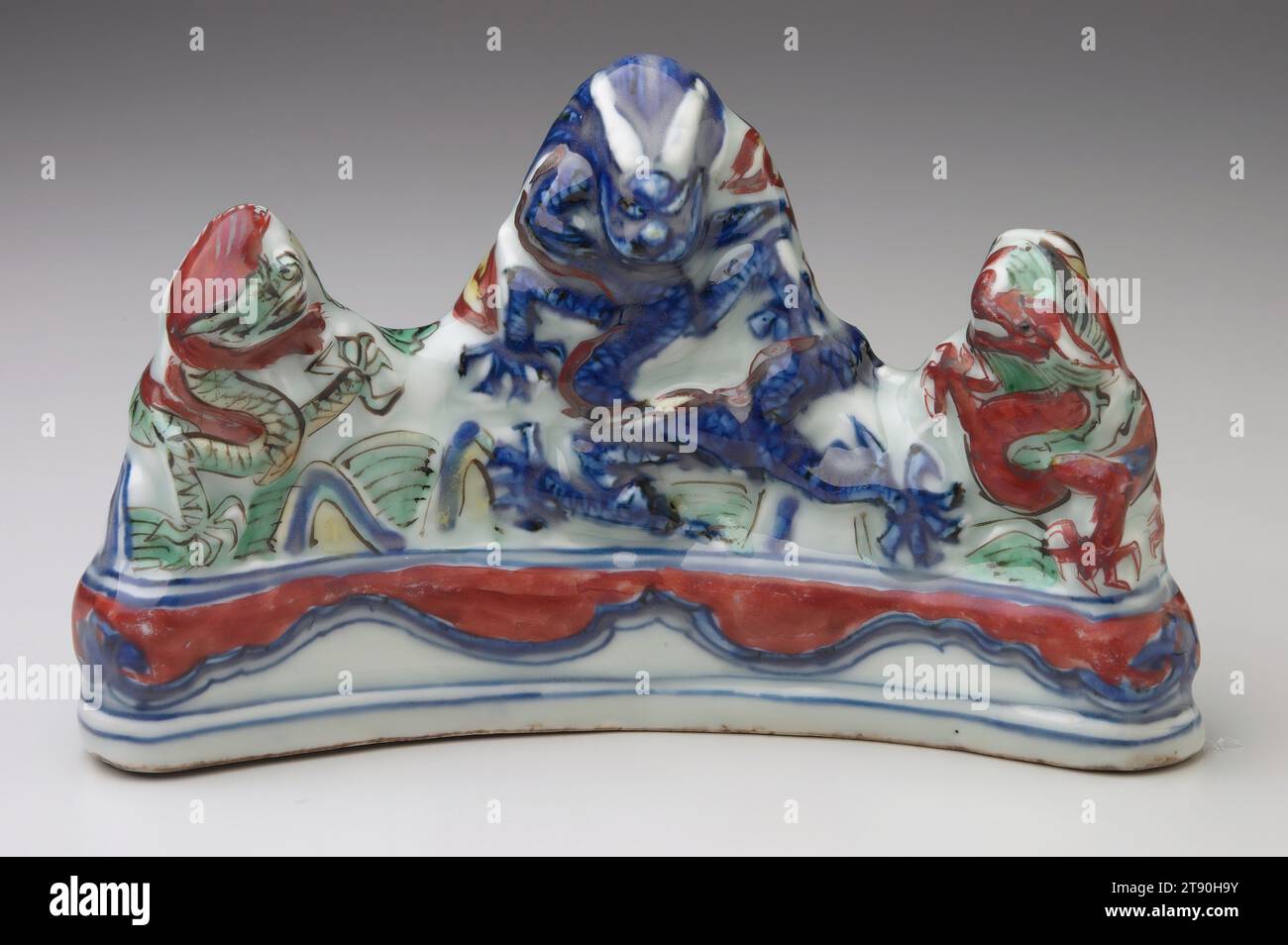 Drei-Drachen-Bürstenauflage, Wanli-Marke und Periode (1573-1619), 4 1/8 x 6 5/8 x 2 9/16" (10,5 x 16,8 x 6,5 cm), Wucai Porzellan mit Unterglasurblau und polychromer Überglasung Emaildekor, China, 16.-17. Jahrhundert, unter der Schirmherrschaft von Ming führten Töpfer in Ching-te-chen eine Reihe von feinen Porzellanen ein, die mit neuen und verbesserten Überglasurfarben verziert sind. Der Begriff wu-TS'ai bedeutet „fünf Farben“, aber er wurde allgemein verwendet, um „polychrom“ zu bedeuten, unabhängig davon, wie viele Farben tatsächlich auf einem Gefäß erschienen. Die Farben der Wu-TS'ai-Überglasung umfassten Rot, Blau, Grün, Gelb und Lila Stockfoto
