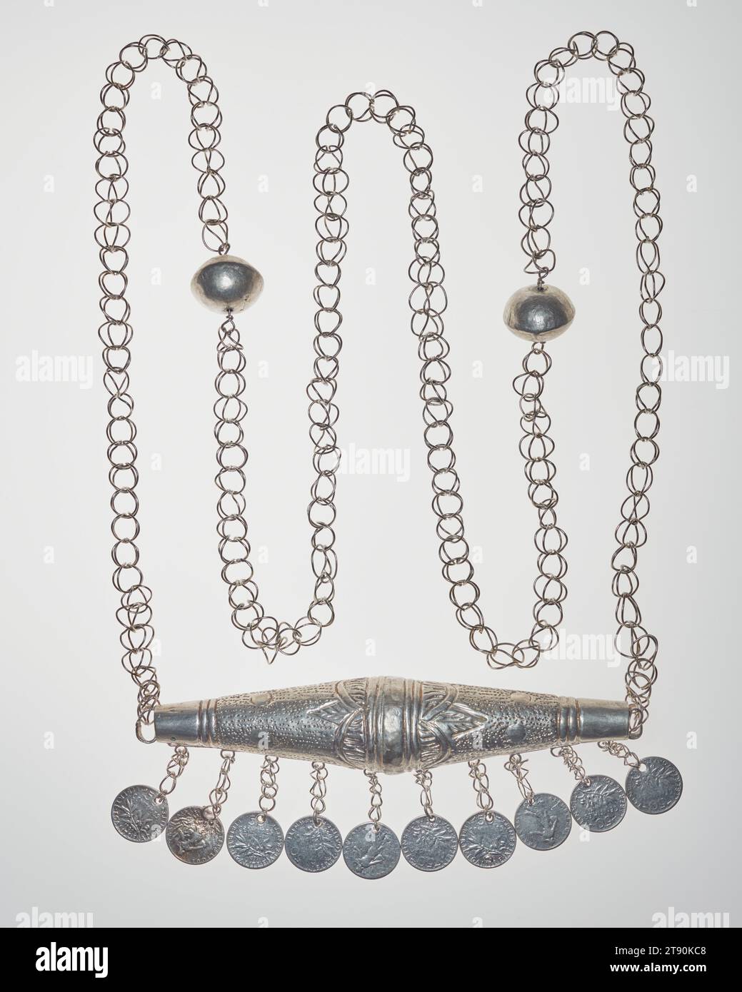 Halskette mit zylinderischem Ornament und Münzanhängern, Ende des 19. Jahrhunderts, 5/8 x 6 1/8 x 3/8 cm (1,59 x 15,56 x 6,03 cm) (nur Ornament), Silver, Benin, 19. Jahrhundert, vor mehr als hundert Jahren hätte die Elite des Königreichs Danhomé in Westafrika diese silbernen Ornamente getragen, um sich zu schmücken und ihren Reichtum zu zeigen und sich vor Schaden und Bösem zu schützen. Die Ornamente wurden von Juwelieren aus importierten Silbermünzen gefertigt und mit winzigen Skulpturen verziert, die auf frühere Könige, heldenhafte Kriege und die Vodun-Religion verweisen. Stockfoto