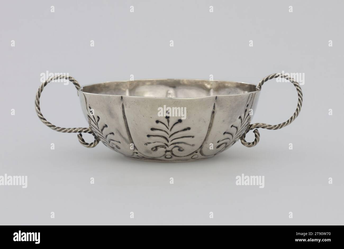 Schüssel mit zwei Griffen, ca. 1690, Jacob Boelen, amerikanisch, 1654-1729, 1/2 x 1/8 Zoll (3,8 x 10,48 cm), Silber, USA, 17.-18. Jahrhundert, Boelen, ein amerikanischer Silberschmied niederländischer Herkunft, der in New York arbeitete, gehörte einer Familie von Silberschmieden an. Dummer war ein prominenter Bostoner Geschäftsmann und Kirchenführer und arbeitete als Silberschmied. Boelens Schüssel erinnert an die zeitgenössischen niederländischen Schalen mit ihrer Aufteilung in sechs Lappen und stark gejagten Dekoration. Durch die Verfolgung wird das Metall verdrängt, sodass das Design sowohl außen als auch innen sichtbar ist. Die Griffe bestehen aus Draht Stockfoto