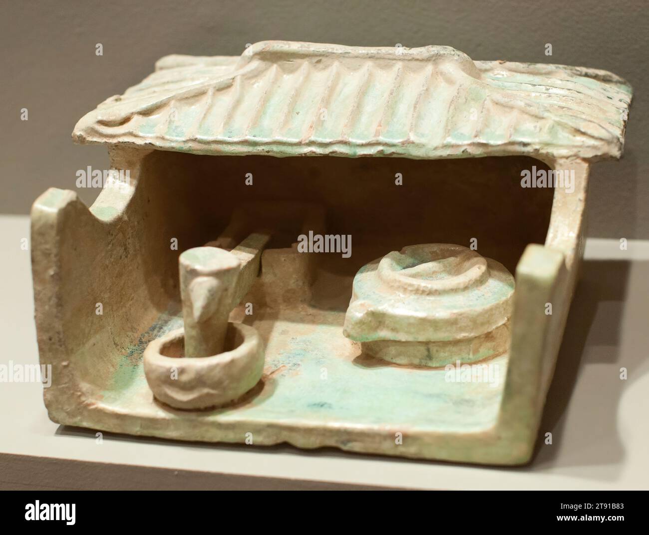 Fräsfach, 206 BCE - 220 CE, 5 1/2 x 10 3/4 x 8 1/2 Zoll (13,97 x 27,31 x 21,59 cm), niedrig gebranntes Steingut mit grüner Glasur, China, 3. Jahrhundert v. Chr. bis 3. Jahrhundert n. Chr., hergestellt aus dem orangen Standardkörper von Han grün glasierten Grabmodellen, diese Miniatur-Frässtation verfügt über einen kreisförmigen Mühlstein und einen fußbetriebenen Mörtel und Pisle Getreidepünder unter dem Dach des Schuppens. Diese beiden landwirtschaftlichen Werkzeuge sind noch immer im ländlichen China im Einsatz. Han-Gräber bieten eine Fülle von landwirtschaftlichen Modellen, die den Glauben widerspiegeln, dass die Landwirtschaft für den Wohlstand des Landes von grundlegender Bedeutung war Stockfoto