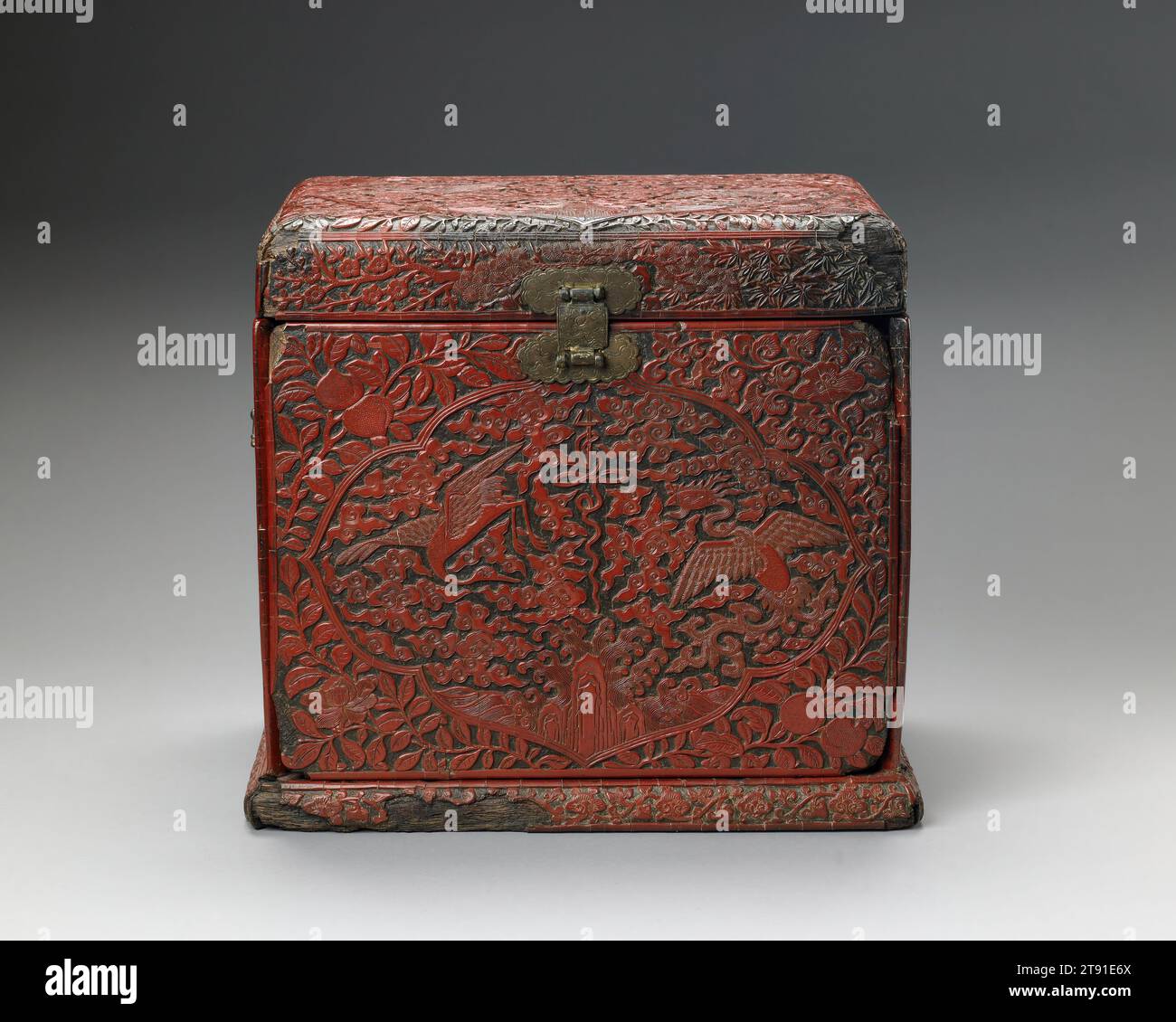 Kosmetikschrank, 16. Jahrhundert, 12 1/8 x 13 3/8 x 9 1/2 Zoll (30,8 x 33,97 x 24,13 cm), geschnitzter roter Lack auf einem Weichholzrahmen, China, 16. Jahrhundert, eine gravierte und vergoldete Markierung auf der Basis dieser Tischplatte sagt uns, dass es ein Produkt der offiziellen Werkstätten der Jiajing-Ära der Ming-Dynastie ist, es stammt aus der Mitte der 1500er Jahre Diese Box zeigt ein reich orchestriertes Schema symbolischer Pflanzen und Tiere. Die Kartuschen oben und an den Seiten zeigen den verheißungsvollen phönix und die Kraniche zwischen Wolken. Auch Symbole für langes Leben erscheinen – der Shou-Charakter (Langlebigkeit) Stockfoto