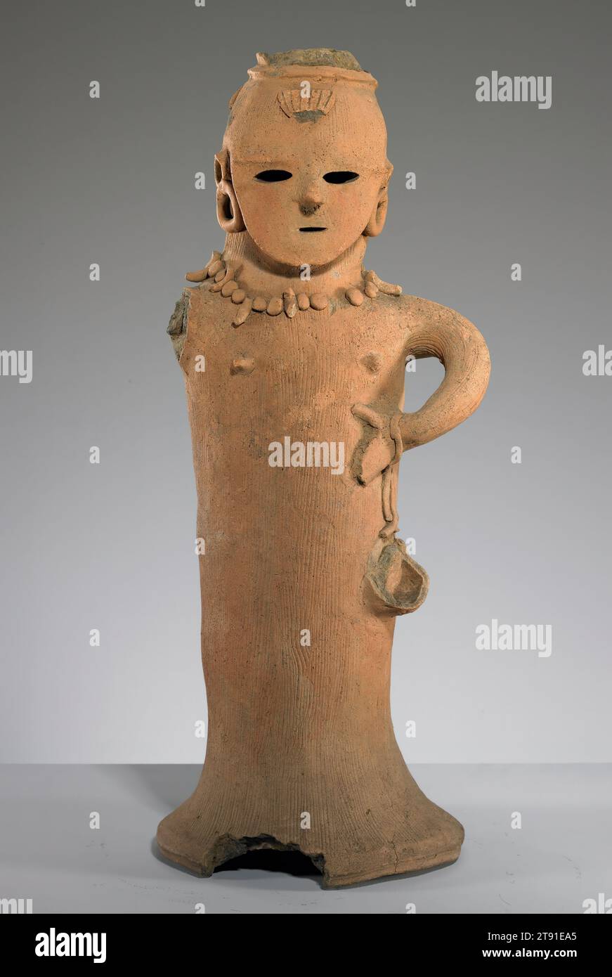 Haniwa of a Female Shrine Attendant, 6th Century, Unknown Japanese, 22 3/8 x 9 3/4 x 8 1/2 Zoll (56,83 x 24,77 x 21,59 cm), Steingut, Japan, 6. Jahrhundert, diese Haniwa, oder eine Grabfigur aus Ton, stellt eine weibliche Figur dar. Ihre Halskette aus magatama (Klauen- oder fangenförmige Juwelen von besonderer Schutzkraft) sagt uns, dass sie eine miko oder Schreinerin ist, eine respektierte Position in der frühen japanischen Gesellschaft. Spuren von roten Pigmenten auf ihren Wangen weisen auf Tätowierungen oder zeremonielle Gesichtsfarbe hin. In ihrem ursprünglichen Zustand trug sie wahrscheinlich eine breite, flache Frisur, die sich über der Stirn erstreckte. Stockfoto