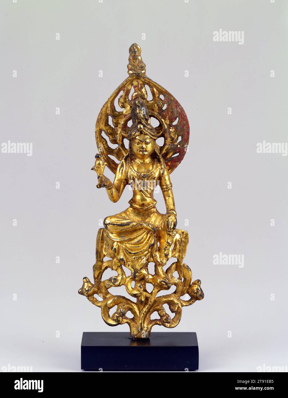 Der Bodhisattva Guanyin, 7. Bis 8. Jahrhundert, 6 1/2 x 2 1/2 x 1 1/4 Zoll (16,51 x 6,35 x 3,18 cm) (insgesamt, einschließlich Sockel), vergoldete Bronze, China, 7.-8. Jahrhundert, ein Bodhisattva ist eine buddhistische Gottheit, die die höchste Stufe der Erleuchtung erreicht hat, aber den Eintritt ins Paradies verzögert, um anderen irdischen Wesen zu helfen. Diese kleine, goldbedeckte Bronzeskulptur zeigt den Bodhisattva Guanyin, eine beliebte Figur unter vielen chinesischen Buddhisten, die für sein Mitgefühl gegenüber dem Leiden bekannt ist. Hier wird Guanyin in der Position Lalitasana („königliche Leichtigkeit“) präsentiert, die als irdischer Prinz gewirkt wird, um seine Bande zu betonen Stockfoto