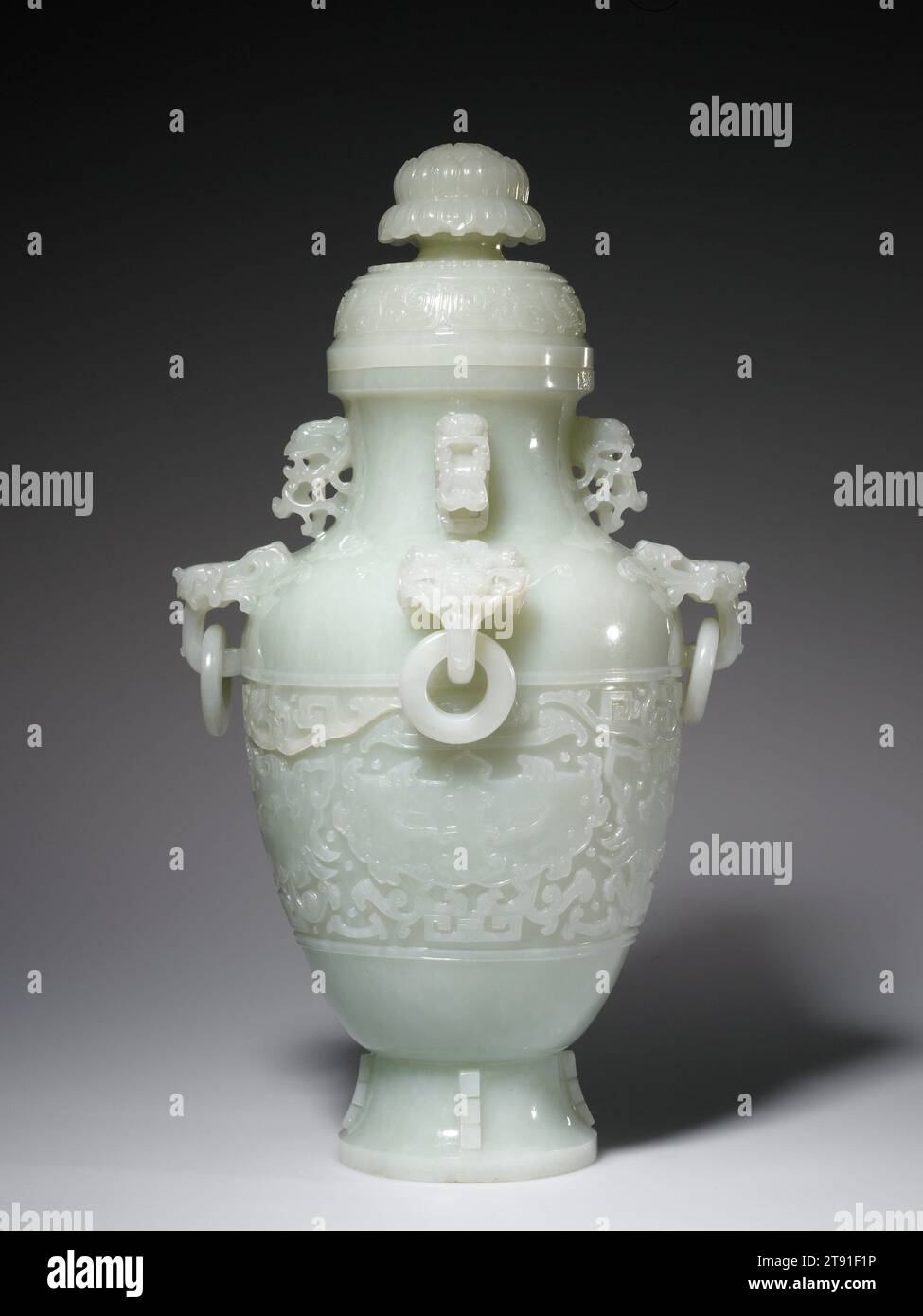 Überdachte Vase, 18. Jahrhundert, 5/8 x 1/2 cm (37,15 x 21,59 cm), weißer Nephrit, China, 18. Jahrhundert, dieser große, die verzierte Vase ist so geformt, dass sie ein altes bronzenes Weingefäß vage imitiert. Acht Ohren ragen von Hals und Schulter der Vase: Vier am Hals sind in Form eines Vogels geschnitzt, die an der Schulter in Form einer Tiermaske mit losen Anhängerringen. Der Hauptbereich der Dekoration ist mit Tiermasken gemeißelt, wie sie häufig auf alten Bronzeschiffen zu finden sind. Der hohe Deckel ist mit einem Band aus phoenix-Designs und einem stilisierten Lotosblüten-Finial verziert Stockfoto