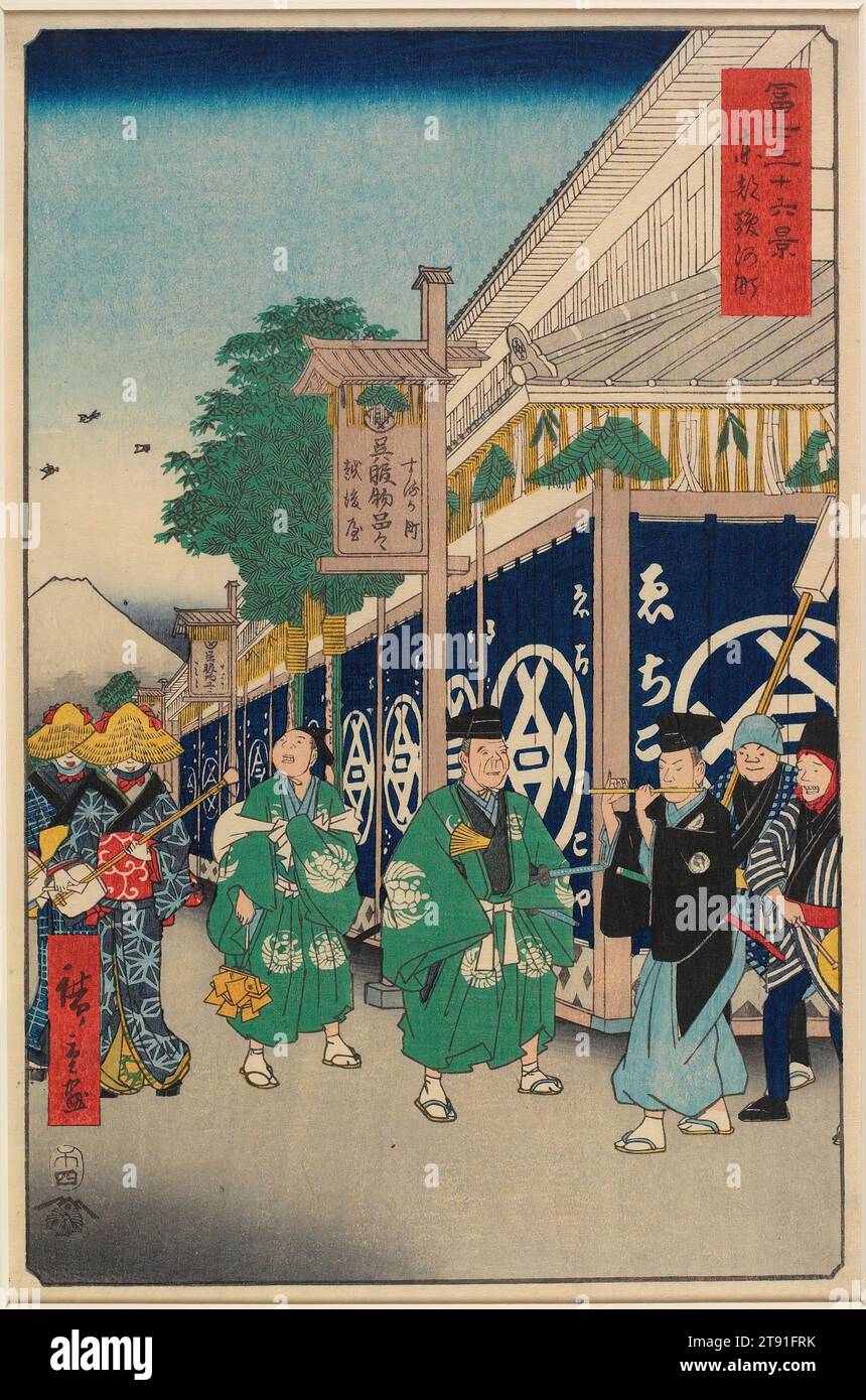 The Suruga District in the Eastern Capital, 1858, 4th Month, Utagawa Hiroshige; Herausgeber: Tsutaya Kichizō, Japanisch, 1797 - 1858, 13 5/16 x 8 11/16 Zoll (33,8 x 22 cm) (Bild, vertikal ōban), Holzblock-Druck (nishiki-e); Tinte und Farbe auf Papier, Japan, 19. Jahrhundert, hier zeigt Hiroshige eine Straßenszene in Suruga-chø bei Nihonbashi. Das Gebäude an der Ecke, wie auf den Vorhängen und dem Holzbrett zu erkennen ist, ist das berühmte Echigoya Textilgeschäft. Ein Strohseil (Shimenawa) mit Farnwedel hängt am Träger des Gebäudes – eine traditionelle Neujahrsdekoration. Stockfoto