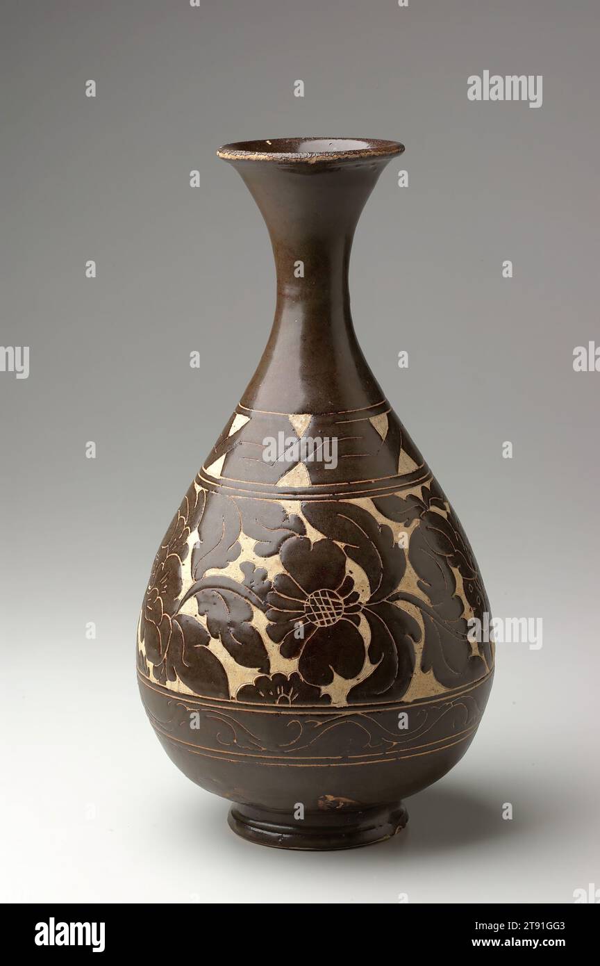 Flasche, 13.-14. Jahrhundert, 10-9/16 x 6-1/2 x 6-1/2 Zoll (26,8 x 16,5 x 16,5 cm), Steinzeug mit Blumendekoration „Cut-glaze“, China, 13.-14. Jahrhundert. Diese wunderschön proportionierte birnenförmige Flasche zeigt ein elegantes Blumendesign, das mit der sogenannten „Cut-glaze“-Technik erreicht wurde. Diese Konstruktion wurde durch Schneiden und Abkratzen der Glasur und Auftragen von Wachs oder Öl auf die freiliegenden Körperbereiche vor dem Brand hergestellt. Die Einschnitte in Verbindung mit dem Resist begrenzen die Glasur erfolgreich auf die gewünschten Bereiche Stockfoto