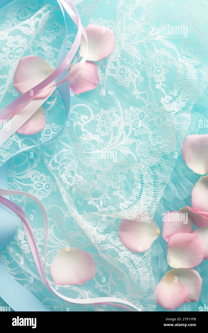 Rosafarbene Rosenblätter und Bänder auf Spitze verstreut Stockfoto